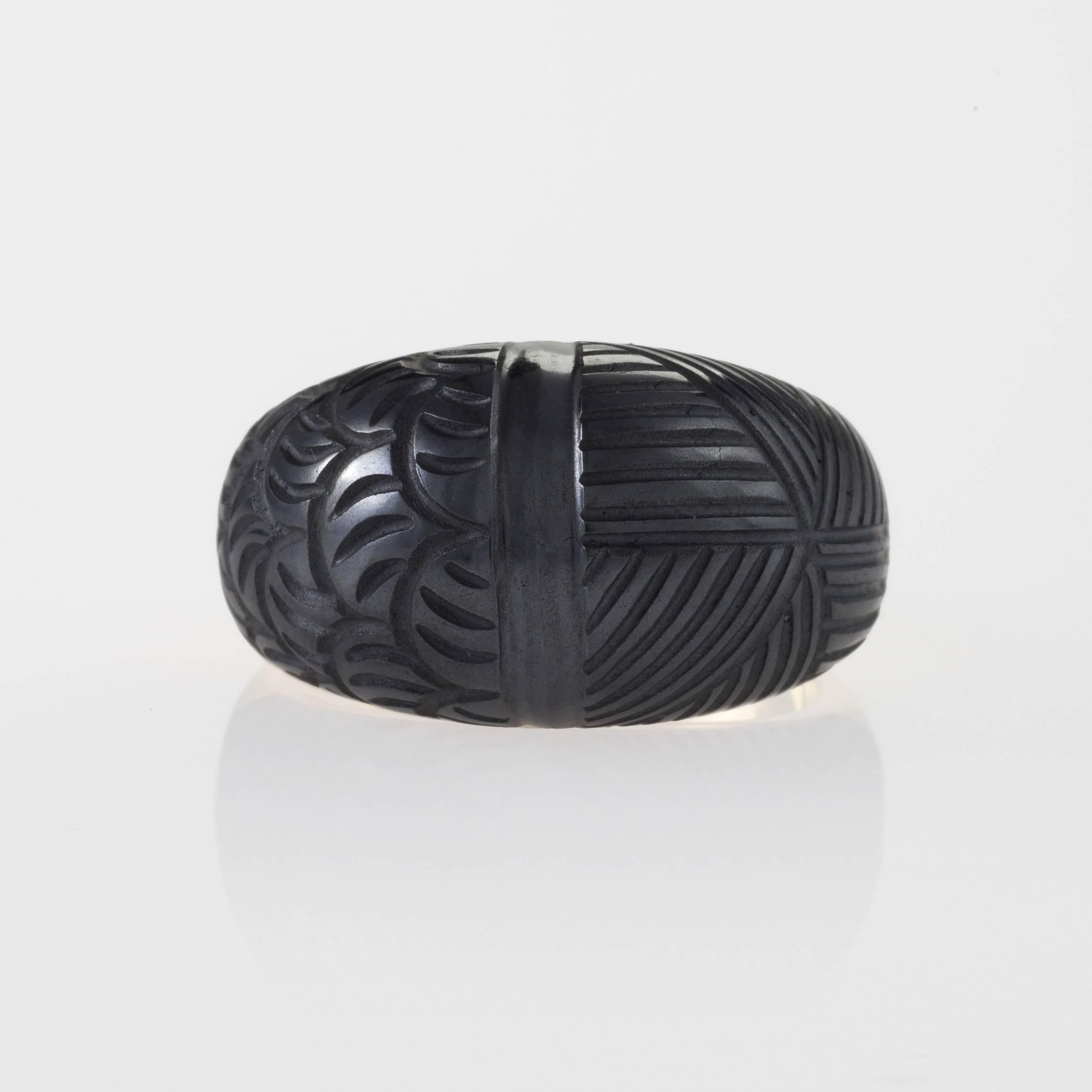 An American Estate 18 karat gold ring with hematite by Carvin French. The ring is composed of a bombé cut hematite with carved geometric tribal carvings.  Circa Estate.

Signed, 