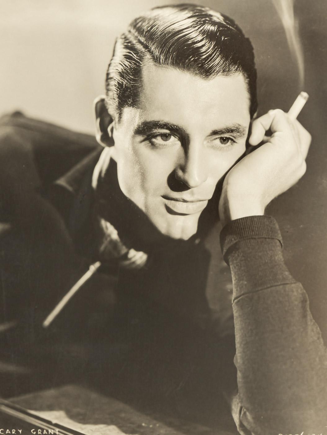 Original vintage Portrait of CARY GRANT. Paramount Studio Portrait from the 1930s showing the actor in a youthful manner with a cigarette in his hand. Framed and ready to hang with passe-partout in a natural wood frame in black behind
