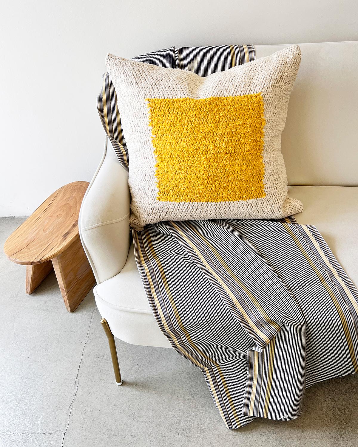 Ein geometrisch strukturiertes Kissen für Ihre Couch oder Ihr Bett. Dieses gelbe und cremefarbene Baumwollkissen ist aus handgewebter Baumwolle gefertigt und eignet sich perfekt für einen stark frequentierten Bereich wie die Wohnzimmercouch. Legen