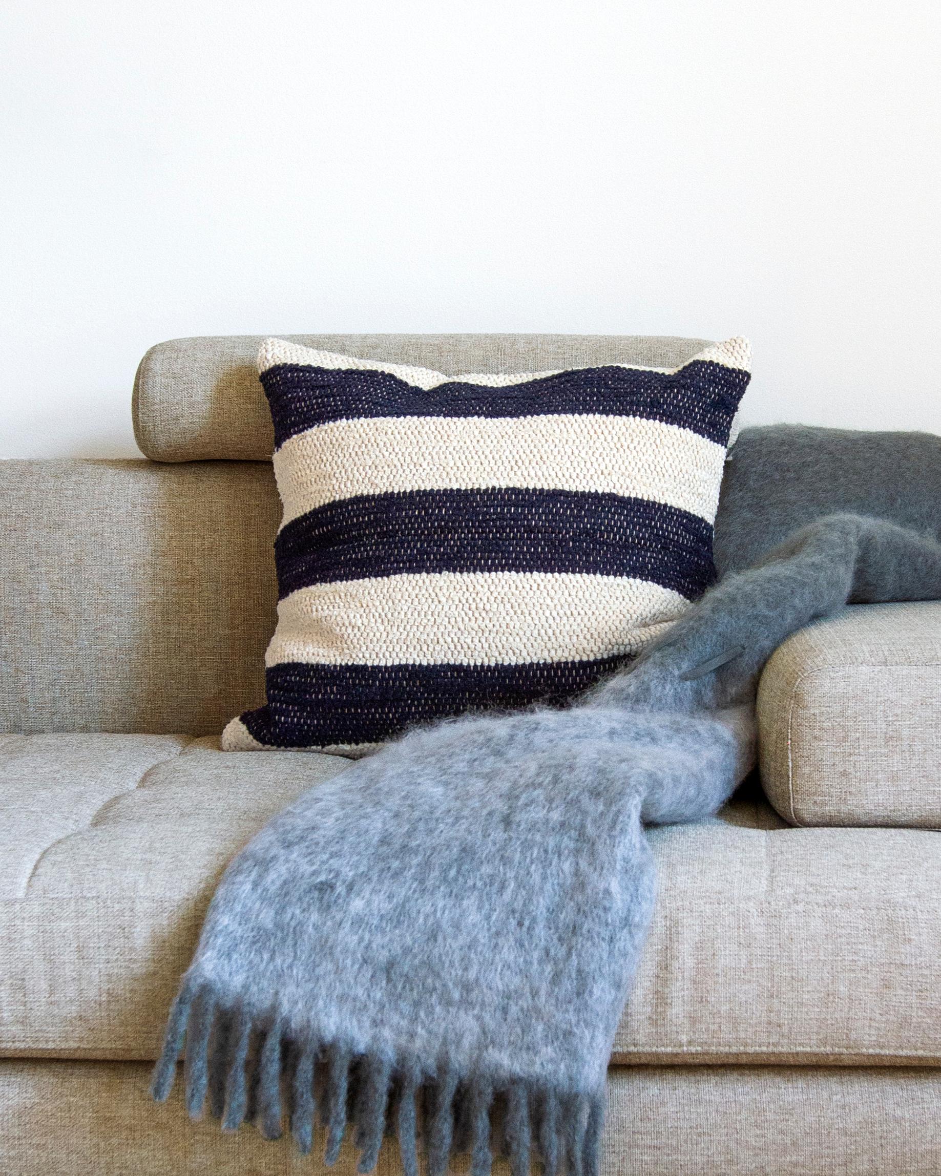 Questo cuscino in cotone color crema e blu è realizzato in cotone spesso tessuto a mano ed è perfetto per una zona ad alto traffico come il divano del soggiorno. Metti due cuscini coordinati su entrambi i lati del divano o prendi più modelli dello