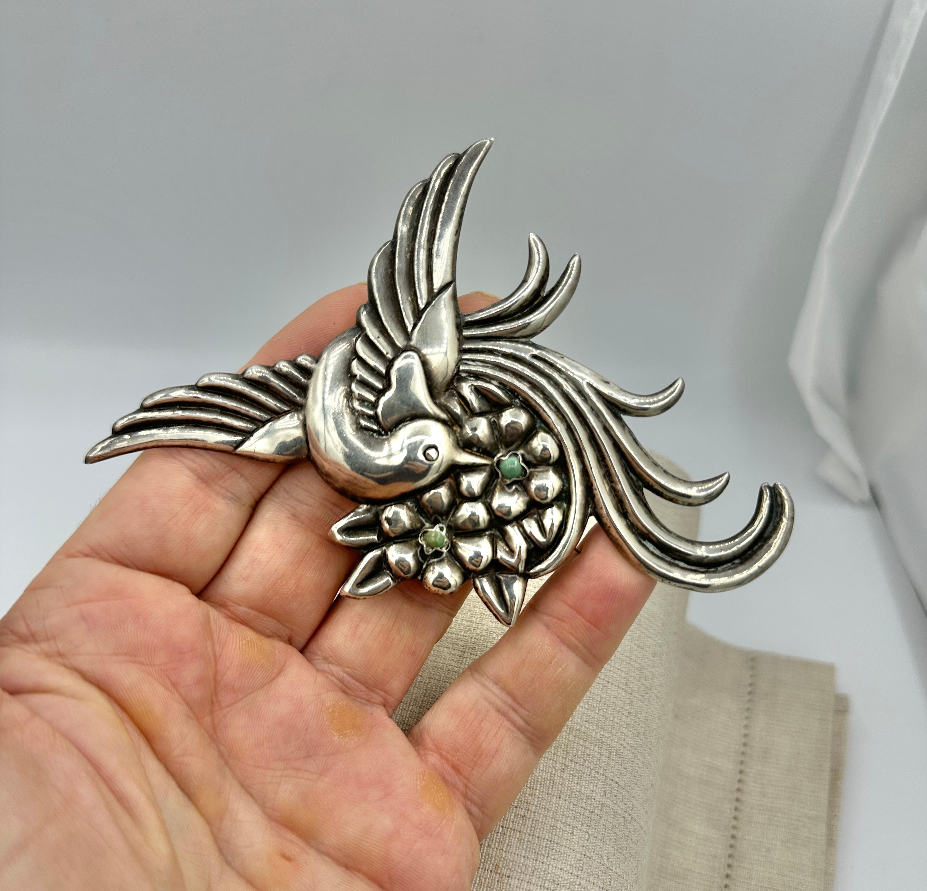 This is a stunning antique Casa Prieto Mexican Sterling Silver and natural Turquoise Brooch in the form of a magnificent Bird of Paradise with a Heart on a Flower Bouquet.  The brooch is a monumental 5 1/4 inches in length.  The deep repouse work is