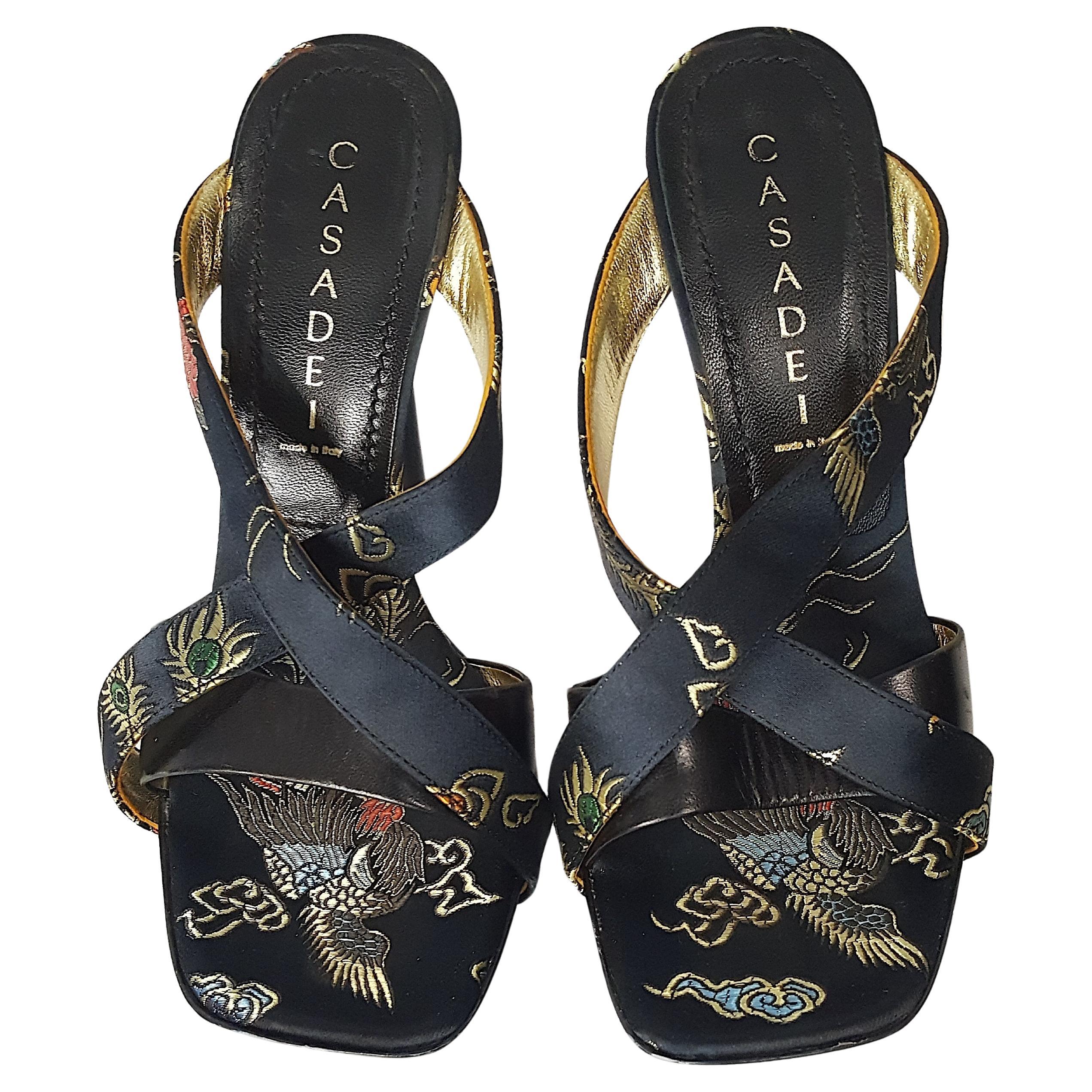 These Casadei limited-edition black patent-leather, calf-leather and ornamental-Chinoiserie metallic-embroidered satin-bound peek-toe sandal mules with towering five-inch heels are supported by a unique platform with cut-out sides, which pay homage
