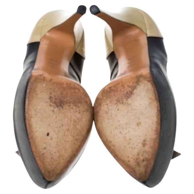Questo paio di splendide décolleté di Casadei è l'emblema della raffinatezza. Questo paio vanta una bellissima struttura in vernice beige e pelle nera. Le classiche décolleté sono impreziosite da fiocchi beige che aggiungono un tocco di femminilità.