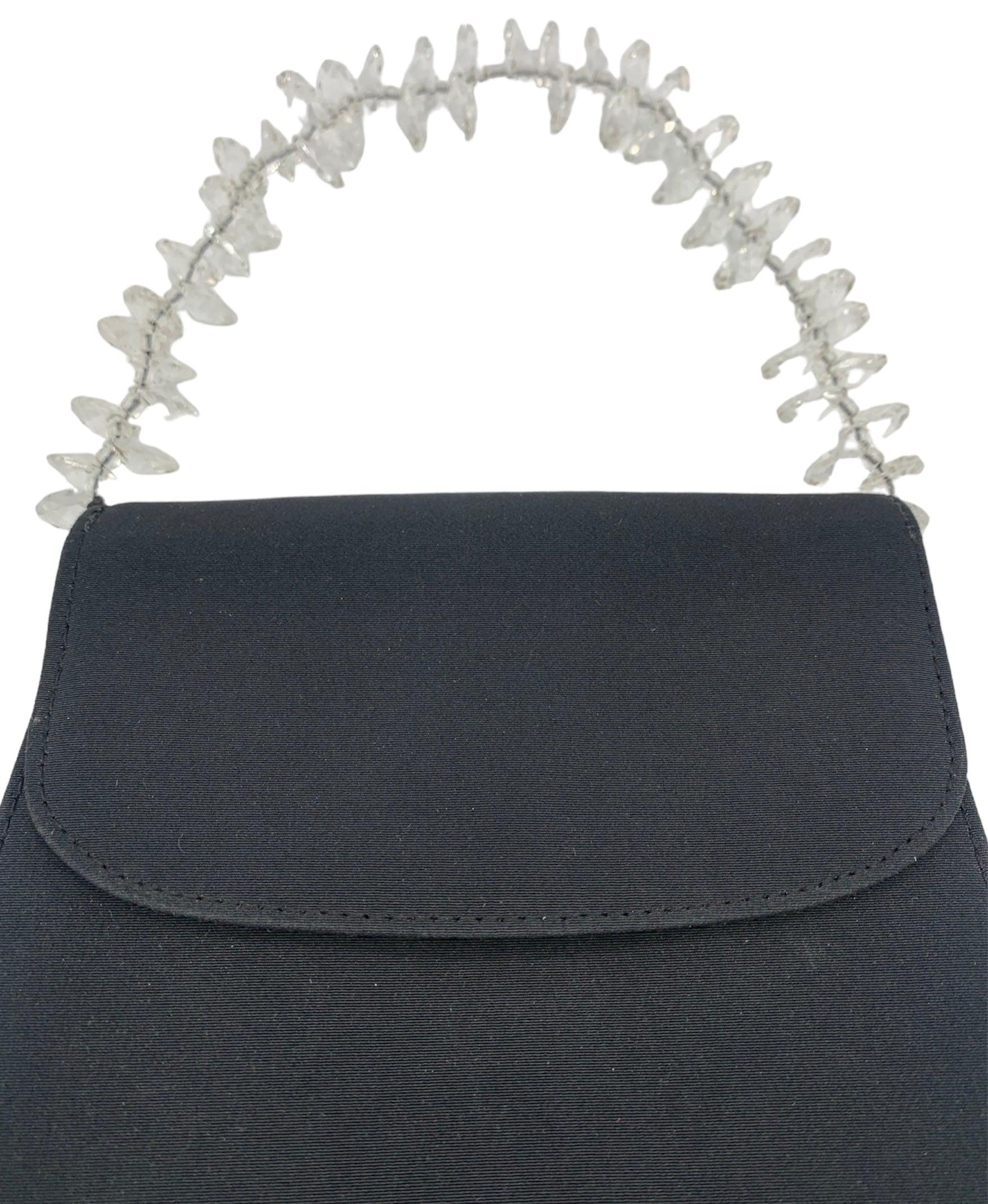 Elegant black faille 90s evening bag from the Italian label Casadei. The perfect size for a night out (yes, it fits a phone). Cascading simulated faceted crystal handle. Magnetic snap closure. One small interior zip pocket. Excellent unworn