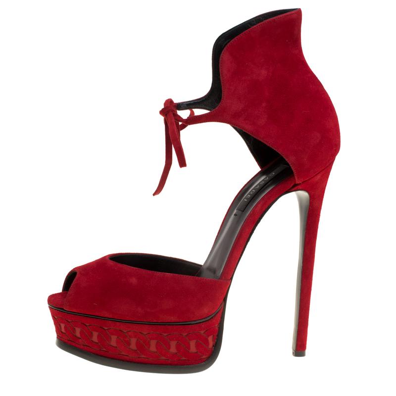 Resplendent and ravishing, these red sandals from Casadei will take your breath away. Crafted from suede, these sandals feature a peep-toe silhouette and flaunt ankle cuffs with tie-ups and solid platforms with chain detailing. They come equipped