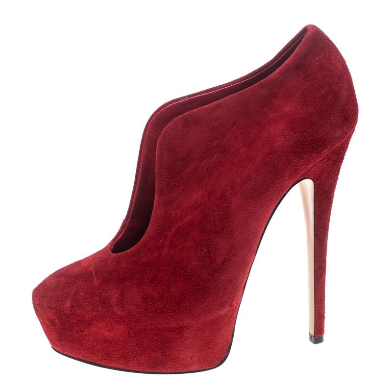 You'll amaze onlookers and fetch admiring glances for every step you take in these gorgeous ankle booties from Casadei! Ravishing in red, they are crafted from suede and feature a slip-on design. They flaunt round toes, an open front silhouette,