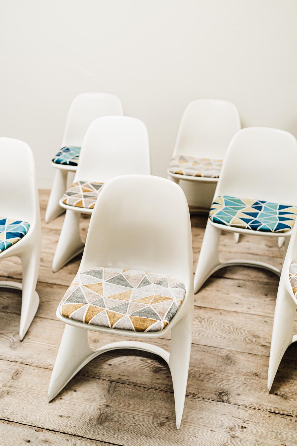 This set of 8 plastic chairs was designed by Alexander Begge in 1971 and manufactured by Casala, Germany. The model Casalino's have ivory colored frames and seats covered with the original fabric.