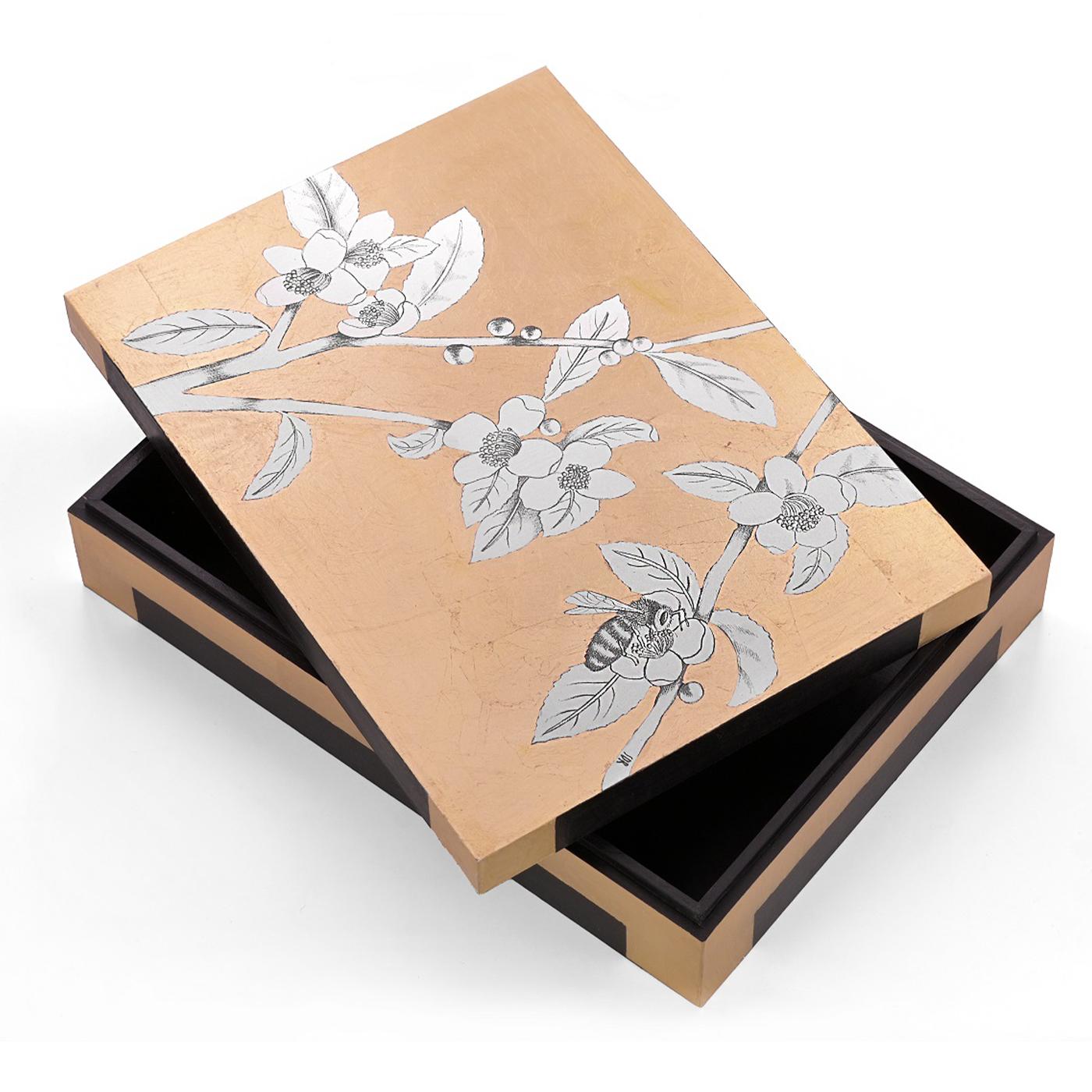 Hand-made box with gold leaf application on graphite drawing. A bee flies from tea flower to tea flower in a gold-sprinkled sky, made by Stefania with her masterful brushstrokes. Entirely decorated by hand with gold leaf on the print of an original