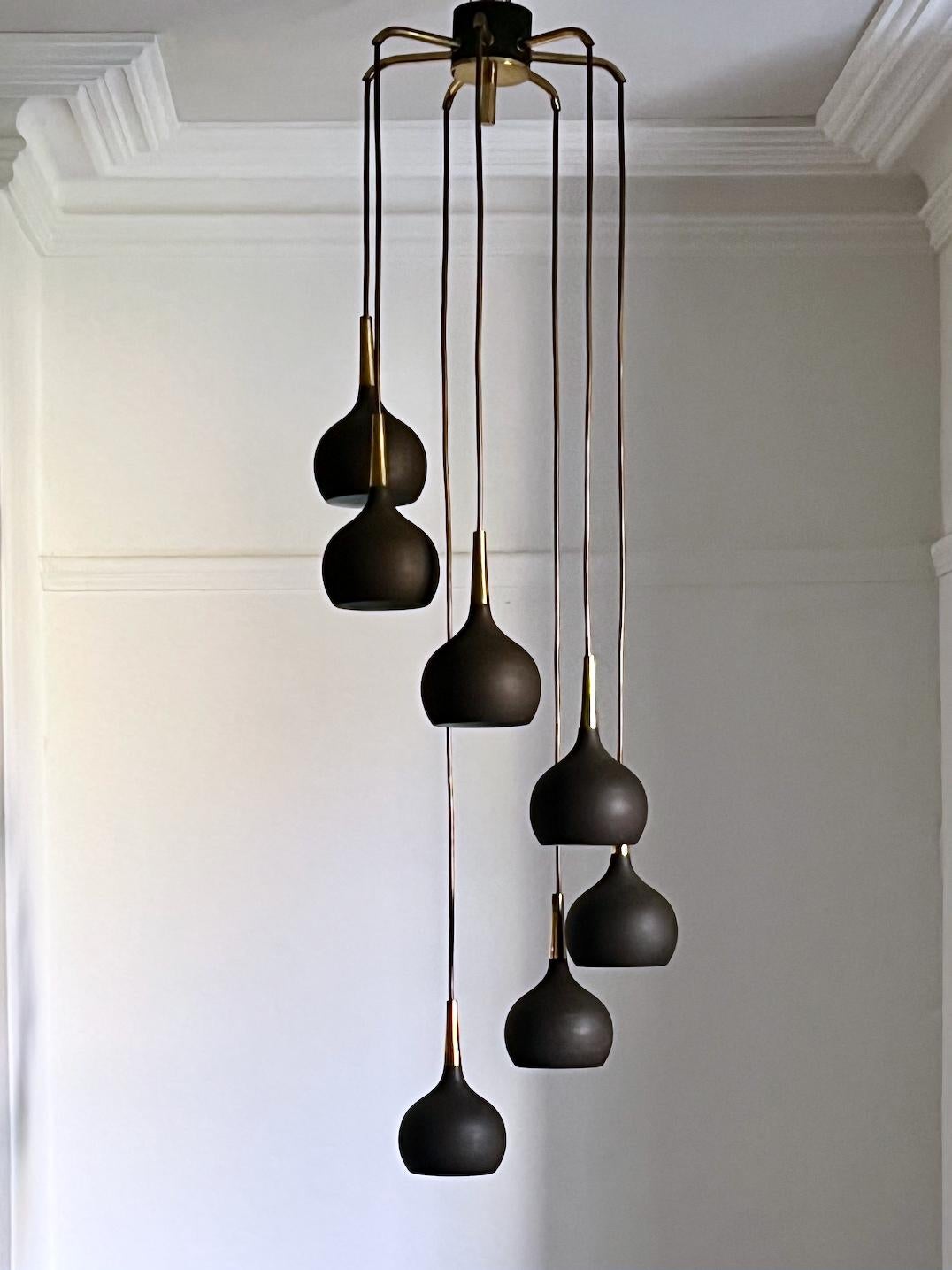 A beautiful midcentury Cascade chandelier by Swedish designer Hans Agne Jakobsson.

The chandelier comprises seven metal shades with charcol-brown finish and brass cones, all hanging from a seven-way brass ceiling canopy. Nicely made with an