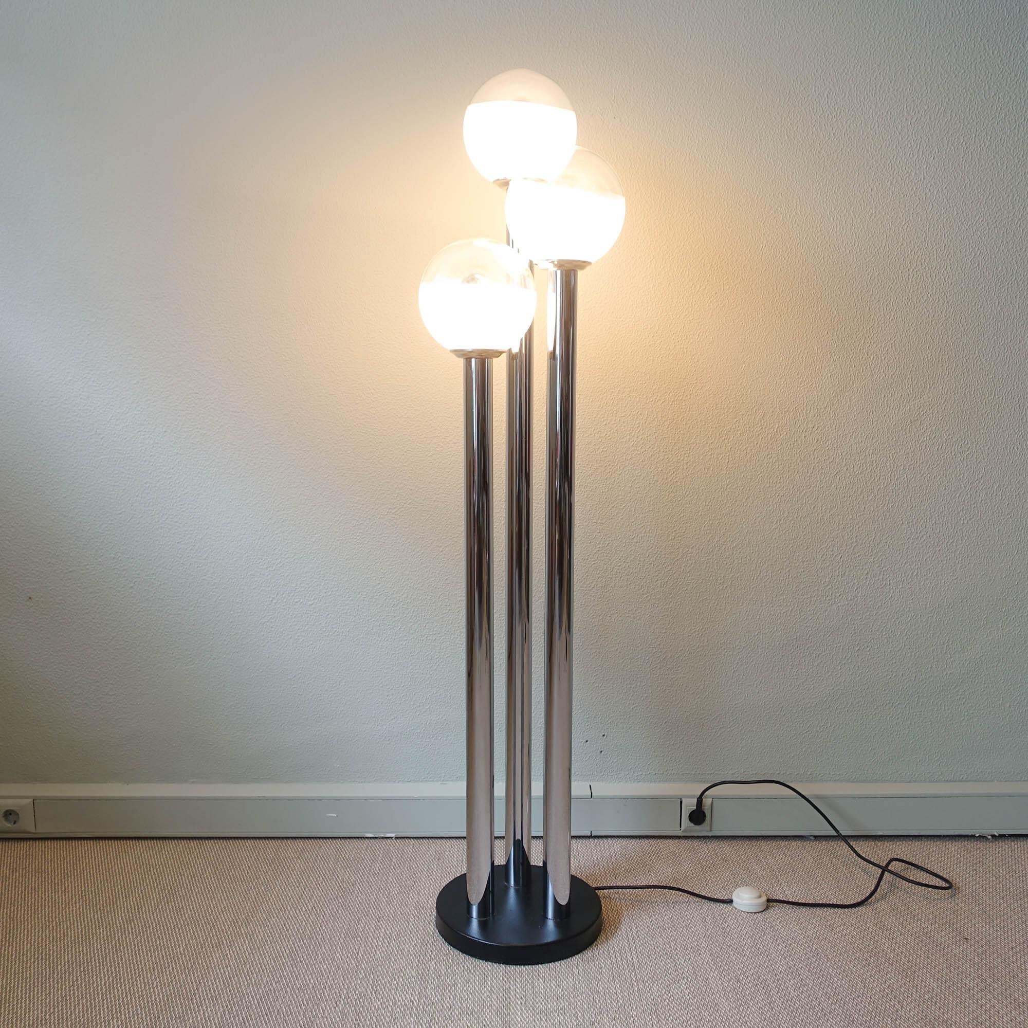 Ce lampadaire a été conçu et produit par Marinha Grande, au Portugal, dans les années 1970. Il présente trois structures tubulaires chromées où sont disposés 3 globes en verre soufflé opalin et transparent.
Le verre est coloré, du lait au