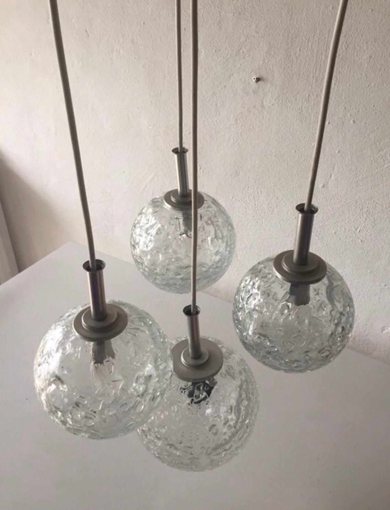 Brand: Doria Leuchten, 1970s, Germany
Made of 3 different sizes ball shaped glasses with matte grey metal tops.
The length of the lampshades can be set individually. The glass balls are structured.
Works with E27 type of bulbs.
 