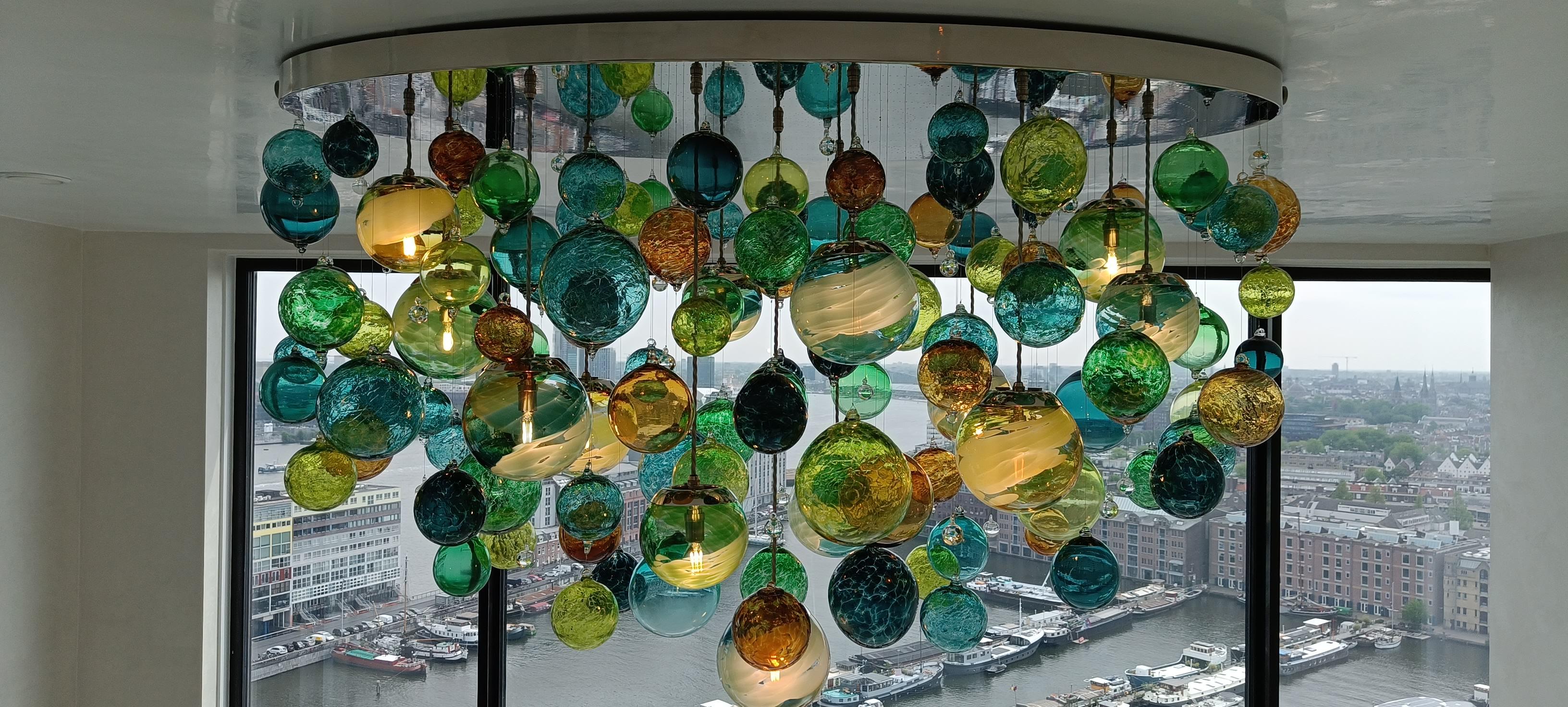 This contemporary chandelier is a Cascade design and featuring individually blown glass spheres. The glass is blown in Europe and the UK and the chandelier is designed and hand-crafted in our studio in South London. 

This oval chandelier frame is