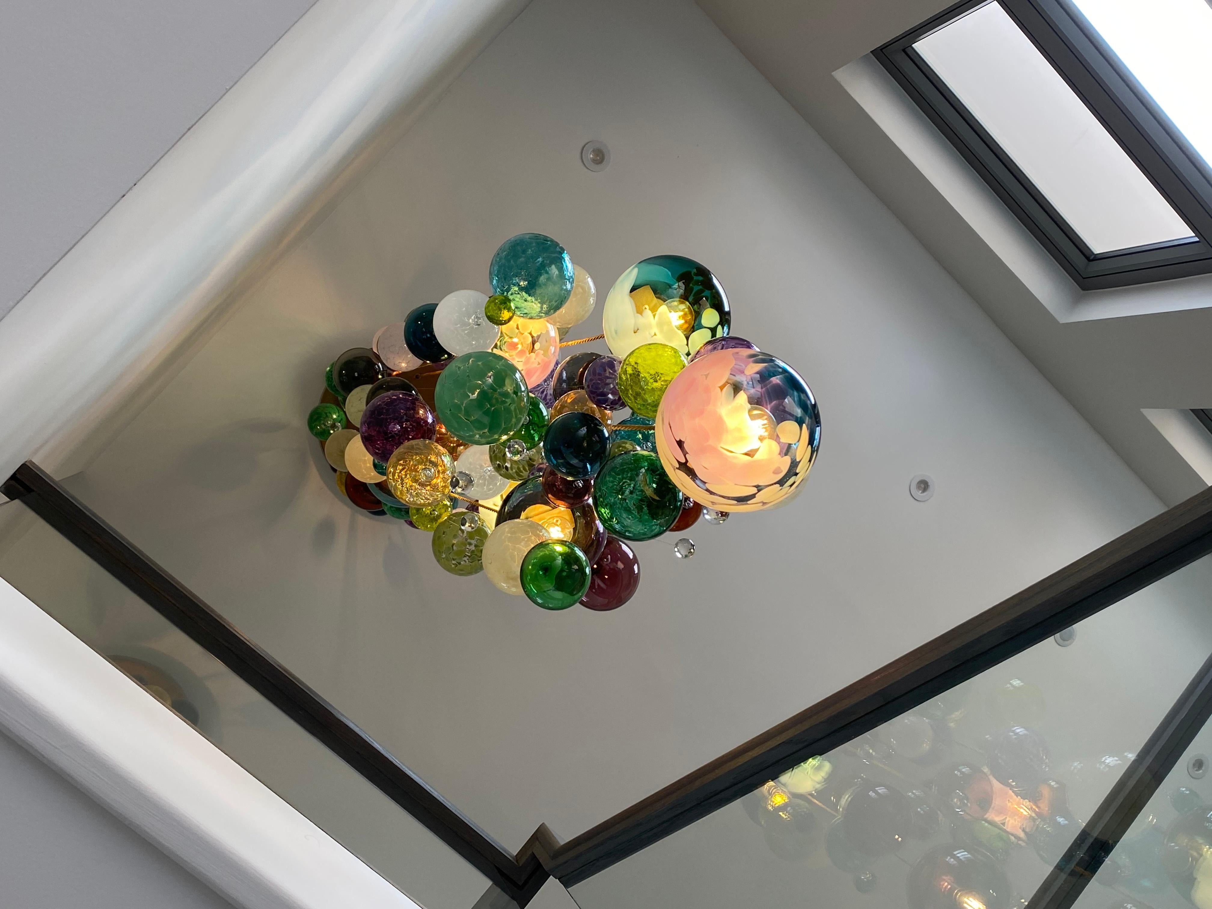 Dieser moderne Kronleuchter im Kaskaden-Design besteht aus einzeln geblasenen Glaskugeln. Das Glas wird in Europa und Großbritannien geblasen und der Kronleuchter wird in unserem Studio in Südlondon entworfen und handgefertigt. 

Dieser Kronleuchter