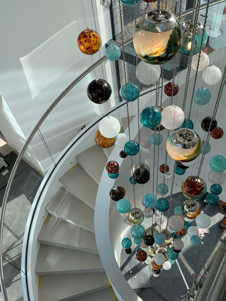 This contemporary stairwell chandelier is a Cascade design and features beautiful individually blown glass spheres. The glass is blown in Europe and the UK and the chandelier is designed and hand-crafted in our studio in South London. 

This