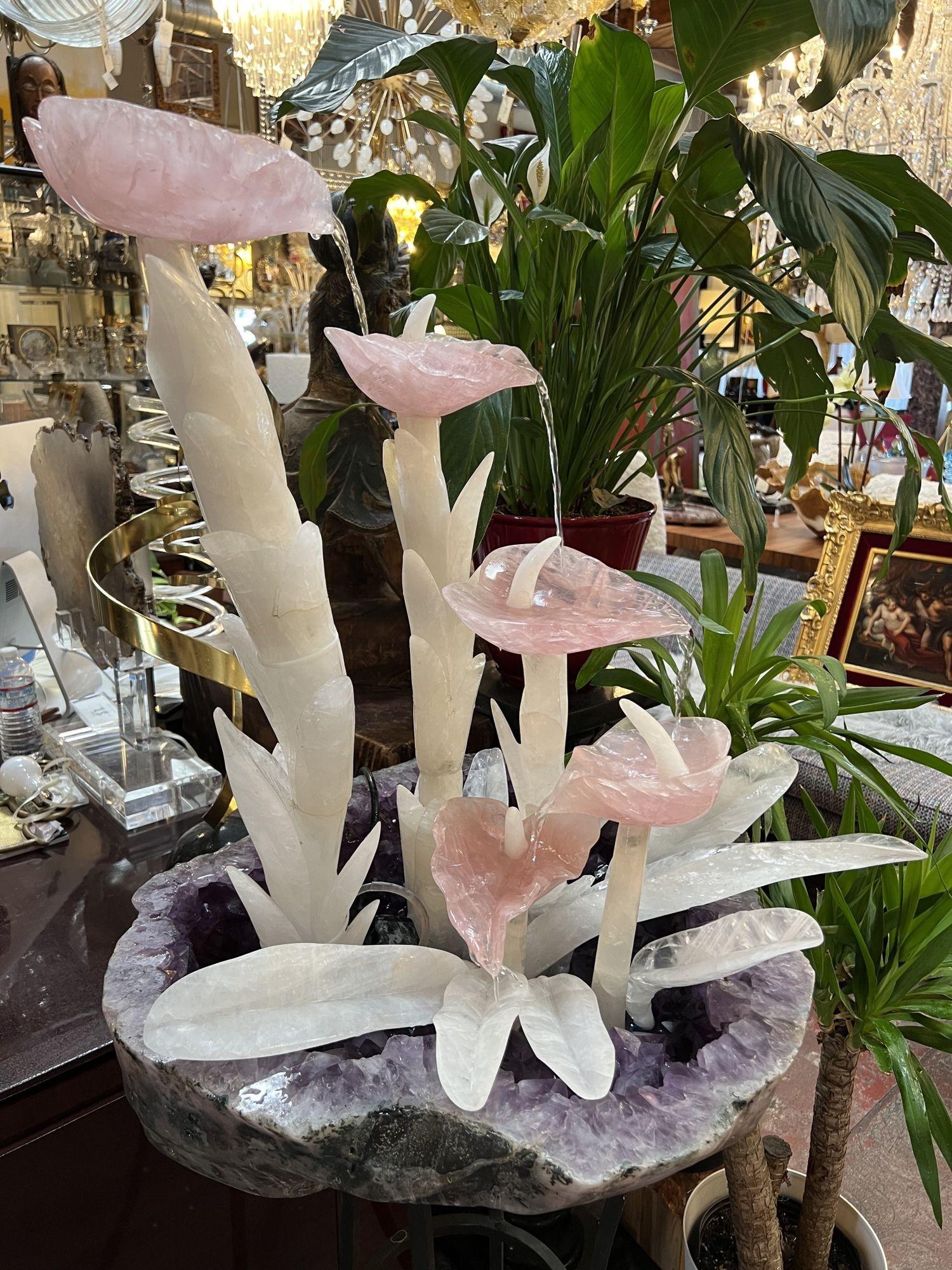 Cascading hand-carved and hand-polished amethyst, rose quartz and rock crystal fountain. The design consists of beautifully hand-carved rose quartz flower petals over carved rock crystal stems blossoming out of a gorgeous large amethyst geode,