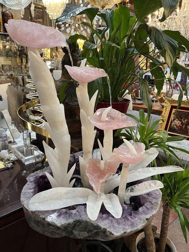 Fuente en cascada tallada y pulida a mano de amatista, cuarzo rosa y cristal de roca. El diseño consiste en pétalos de flor de cuarzo rosa bellamente tallados a mano sobre tallos de cristal de roca tallados que brotan de una magnífica geoda de