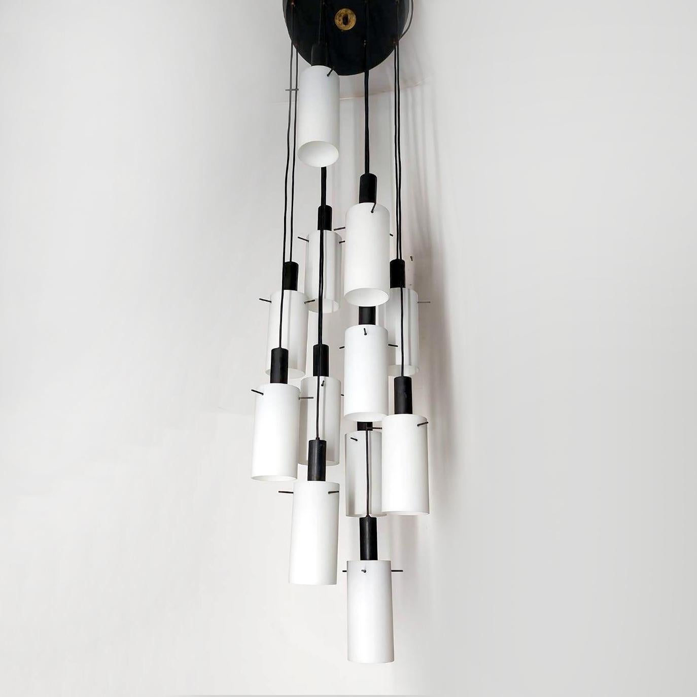 Un lampadario a cascata alla maniera di Stilnovo realizzato in Italia negli anni Settanta in perfette condizioni. Funziona a 110-240 volt e necessita di dieci normali lampadine e14.
Paralume in vetro opalino satinato, supporti in metallo verniciato