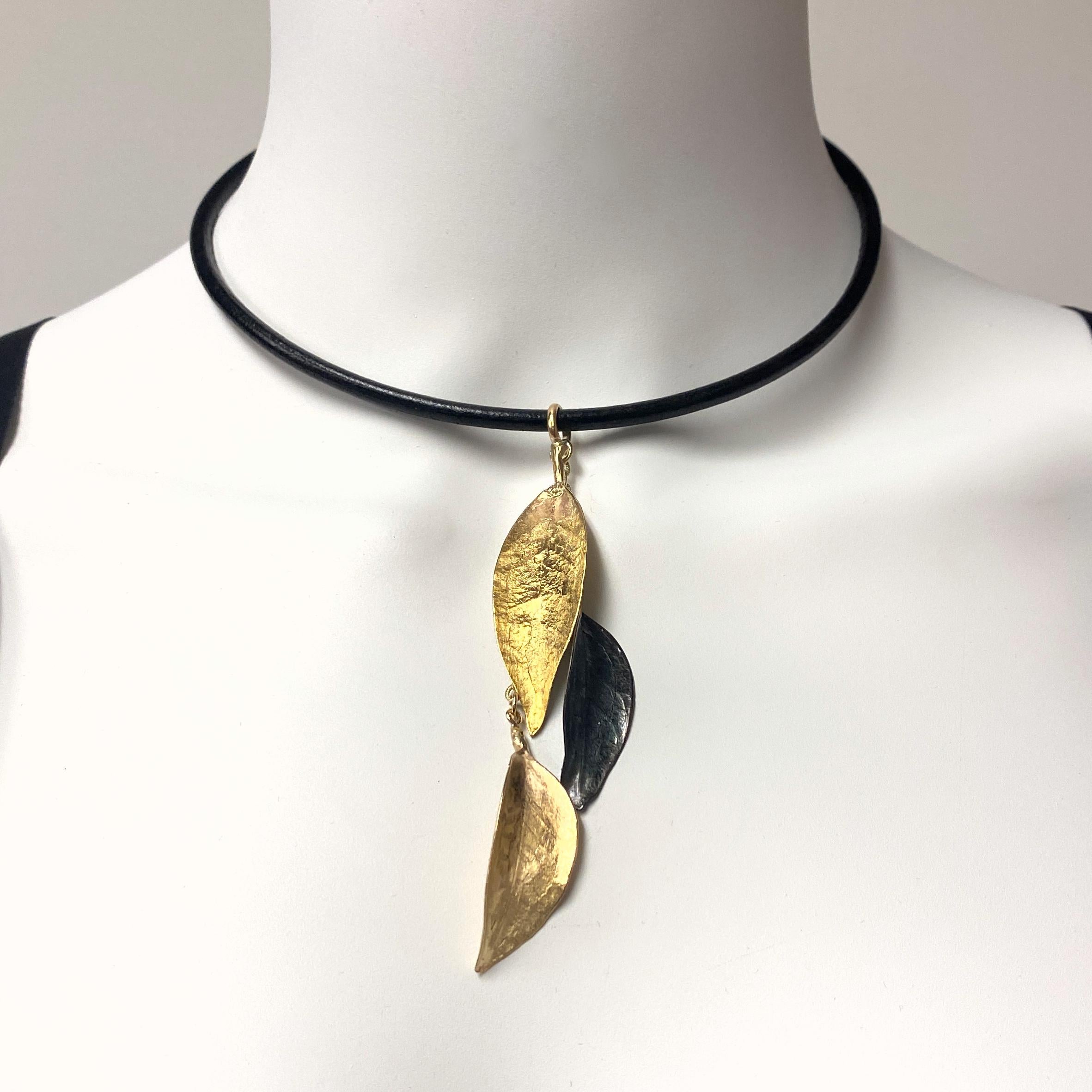 Eytan Brandes used actual leaves to make the wax molds for these leaves, so they're whisper-thin and super-lightweight.  All three leaves are 14 karat gold, but with different finishes.  

The center leaf has been oxidized black.  The top leaf is 14