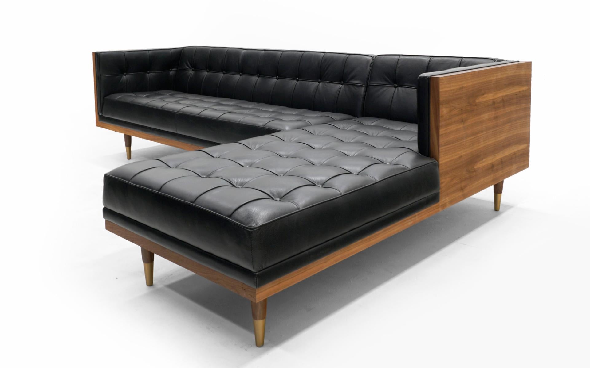 This two piece walnut and leather case sectional sofa with chaise is in virtually unused condition. High quality ufted black aniline dyed leather in the style of a Barcelona daybed. Hardwood walnut case makes this sofa look great from any angle.