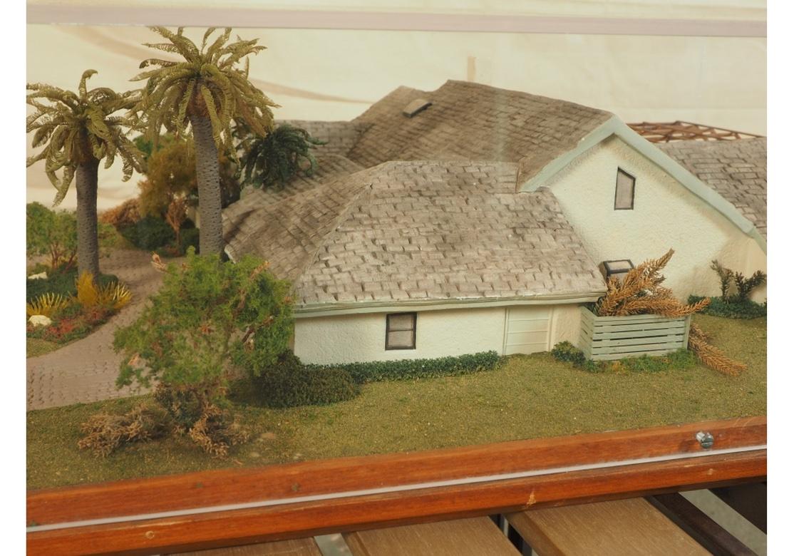 Ein feines, detailliertes Modell-Diorama für einen potenziellen Kunden, möglicherweise in Florida oder Kalifornien. Ein weiß getünchtes vierteiliges Haus mit Giebeldächern und einem durchbrochenen Rahmen für die Veranda, die den Pool und die