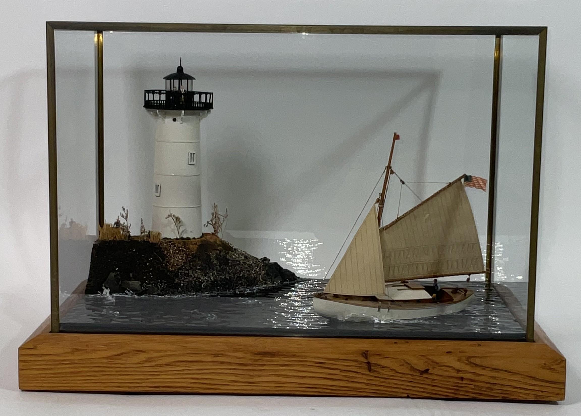 Diorama di un faro su una punta di terra con uno sloop armato di gaff che passa con due persone a bordo. Coperchio in vetro con finiture in ottone.

Peso:    11 libbre.
Dimensioni complessive:    12