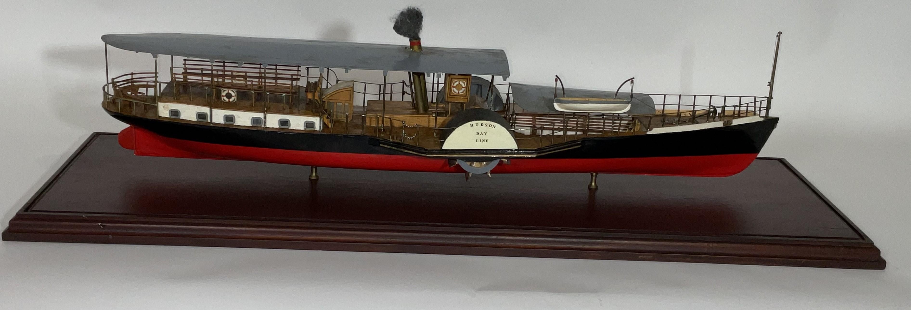 Belle maquette d'un bateau à vapeur à roues à aubes de la ligne Hudson Day. Le pont présente de nombreux espaces pour s'asseoir, la timonerie, les chemins de traverse, les garde-corps, la cheminée à vapeur, etc. Monté dans un coffret en verre sur