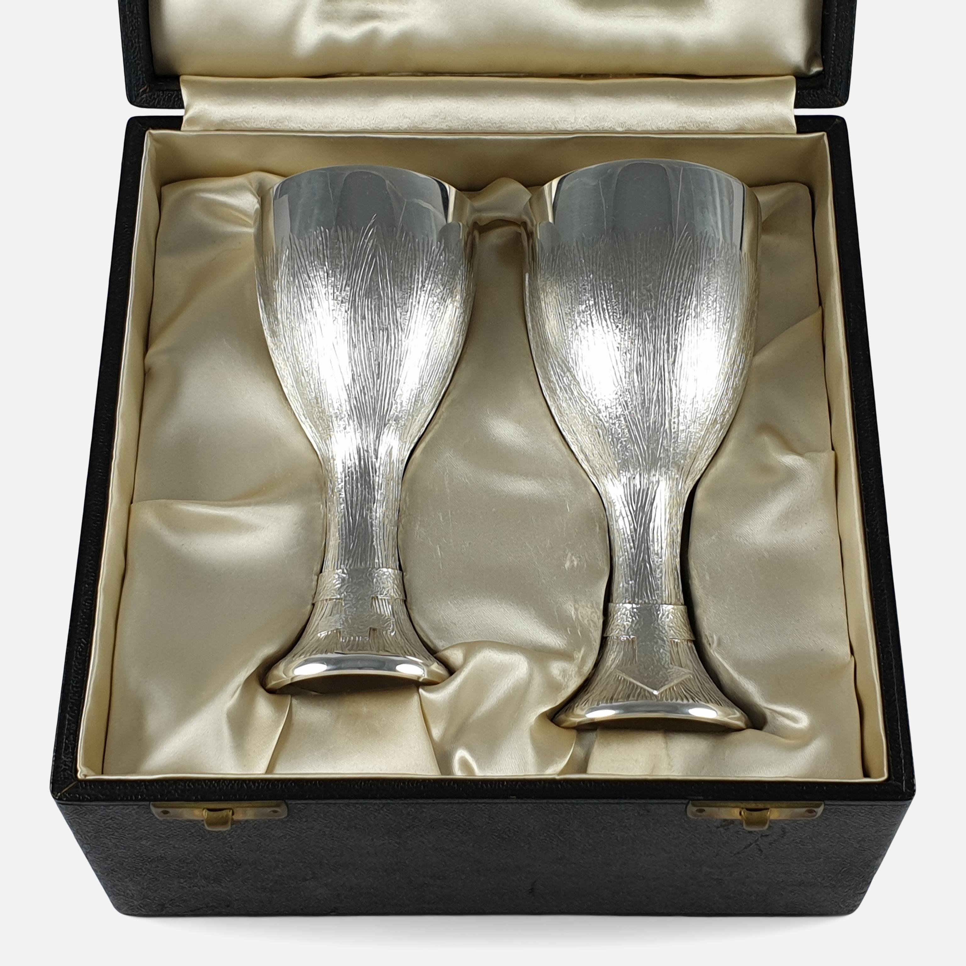 A cased pair of sterling silver court cups by Christopher Lawrence, London, 1974. The silver cups for sale are engraved with finely textured sprays, gilt wash to the interior, with the Mars (male) symbol to the larger cup's foot, and Venus (female)