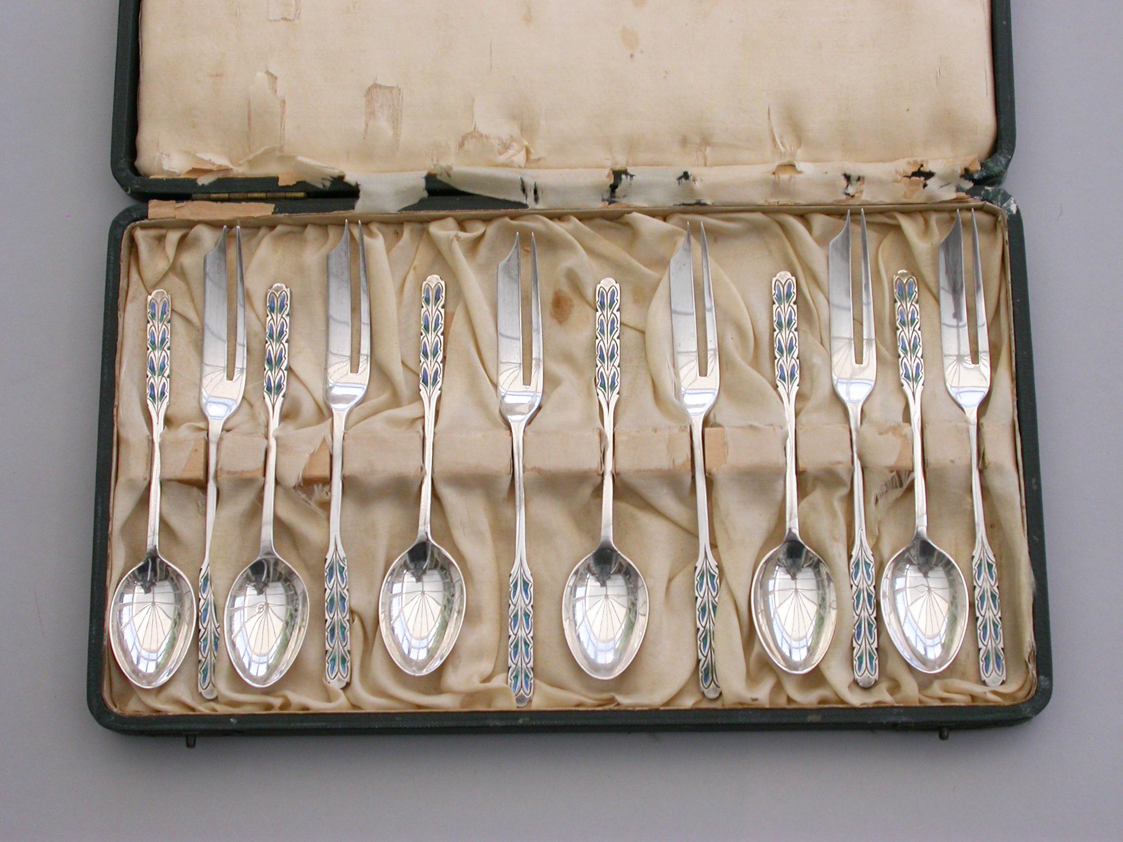 A good cased set of 12 silver and enamel pastry spoons and forks, the handles decorated with a stylised fern pattern in blue and green enamels. Complete with original Liberty retailers case.

By Liberty & Co, Birmingham, 1927 (Forks) 1928