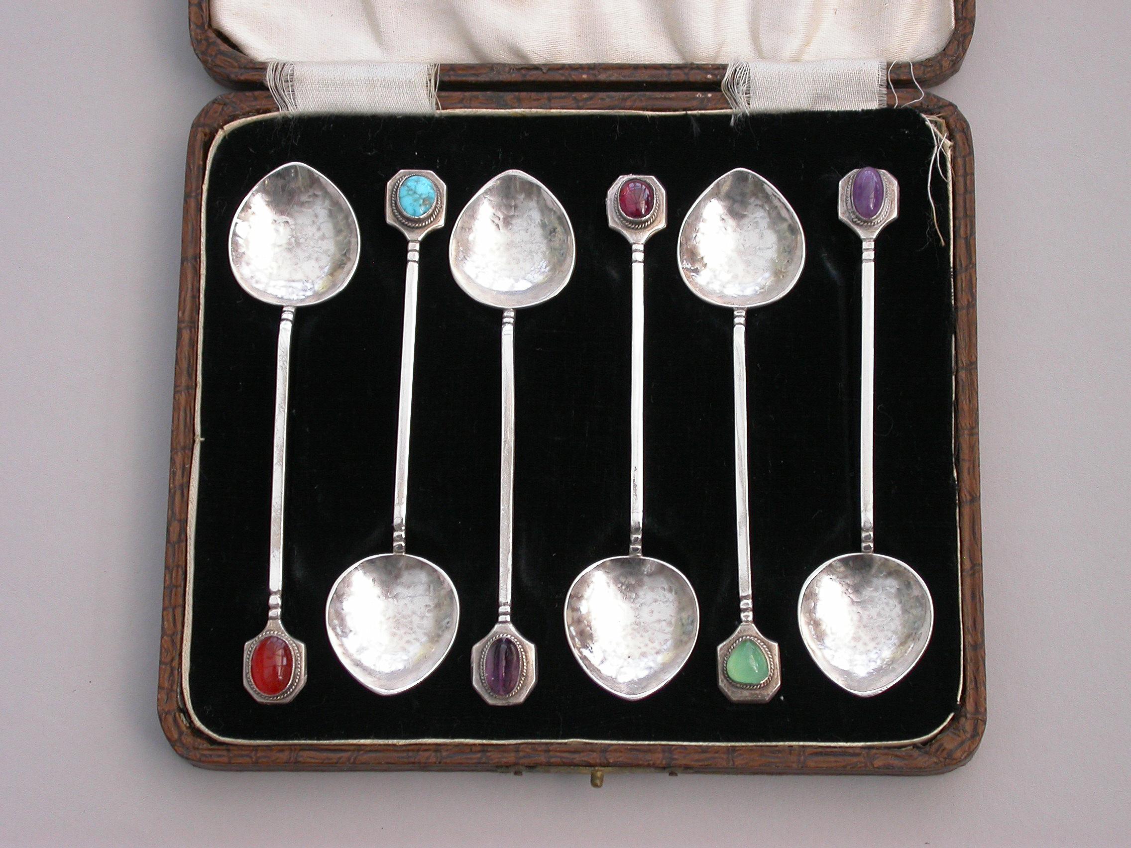 A cased set of six early 20th century Australian Arts & Crafts silver teaspoons with hammered bowls and various different colored hardstone cabochon finials.

Marked :- 'Sterling Silver', probably Australian c1910

60 grams total weight of the