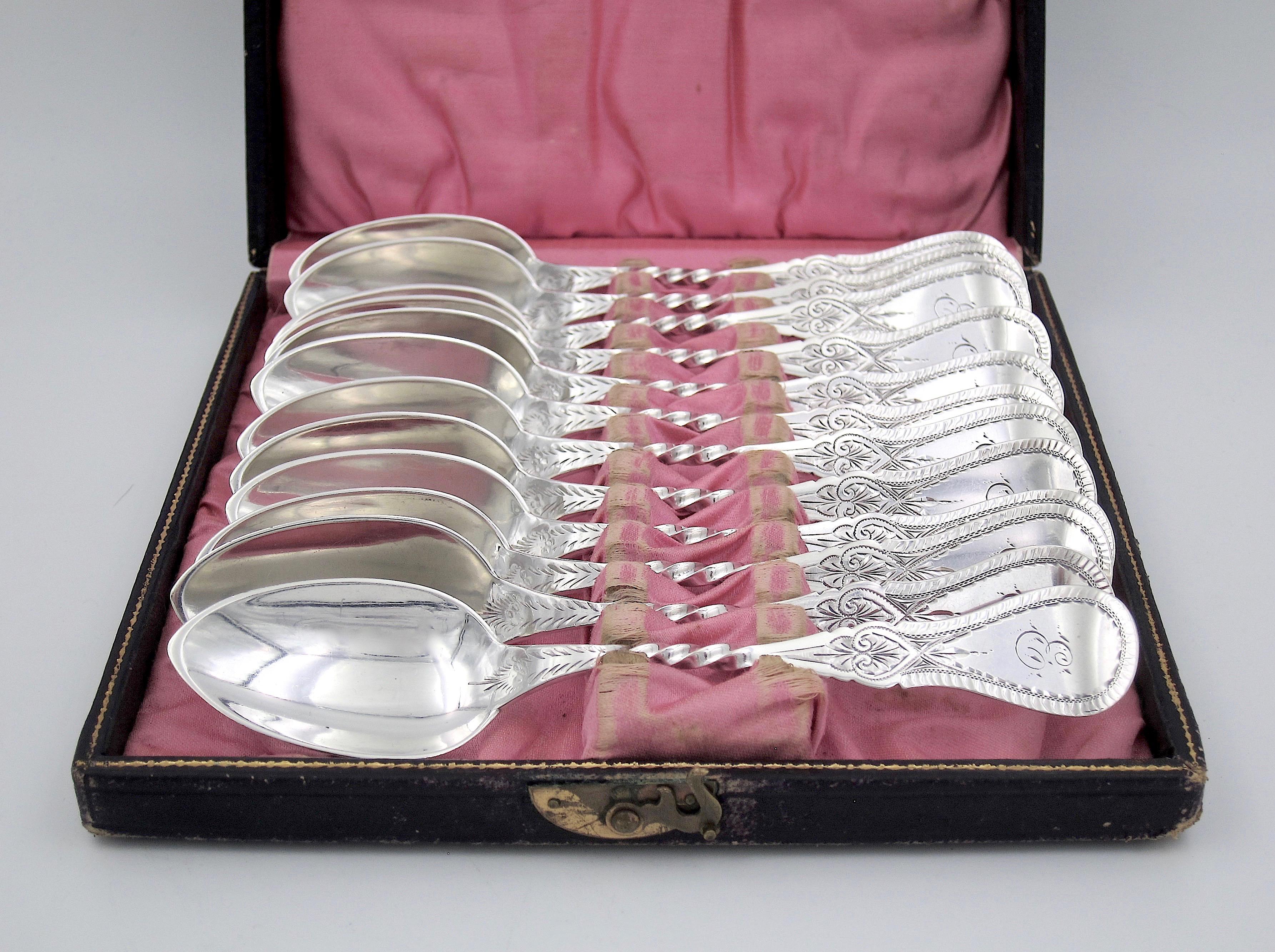 A boxed set of 12 antique coin silver spoons from Philadelphia silversmith James Watts (active 1835-1887). The intricately engraved American silver spoons date to the mid-19th century and remain in their original silk lined presentation box fitted