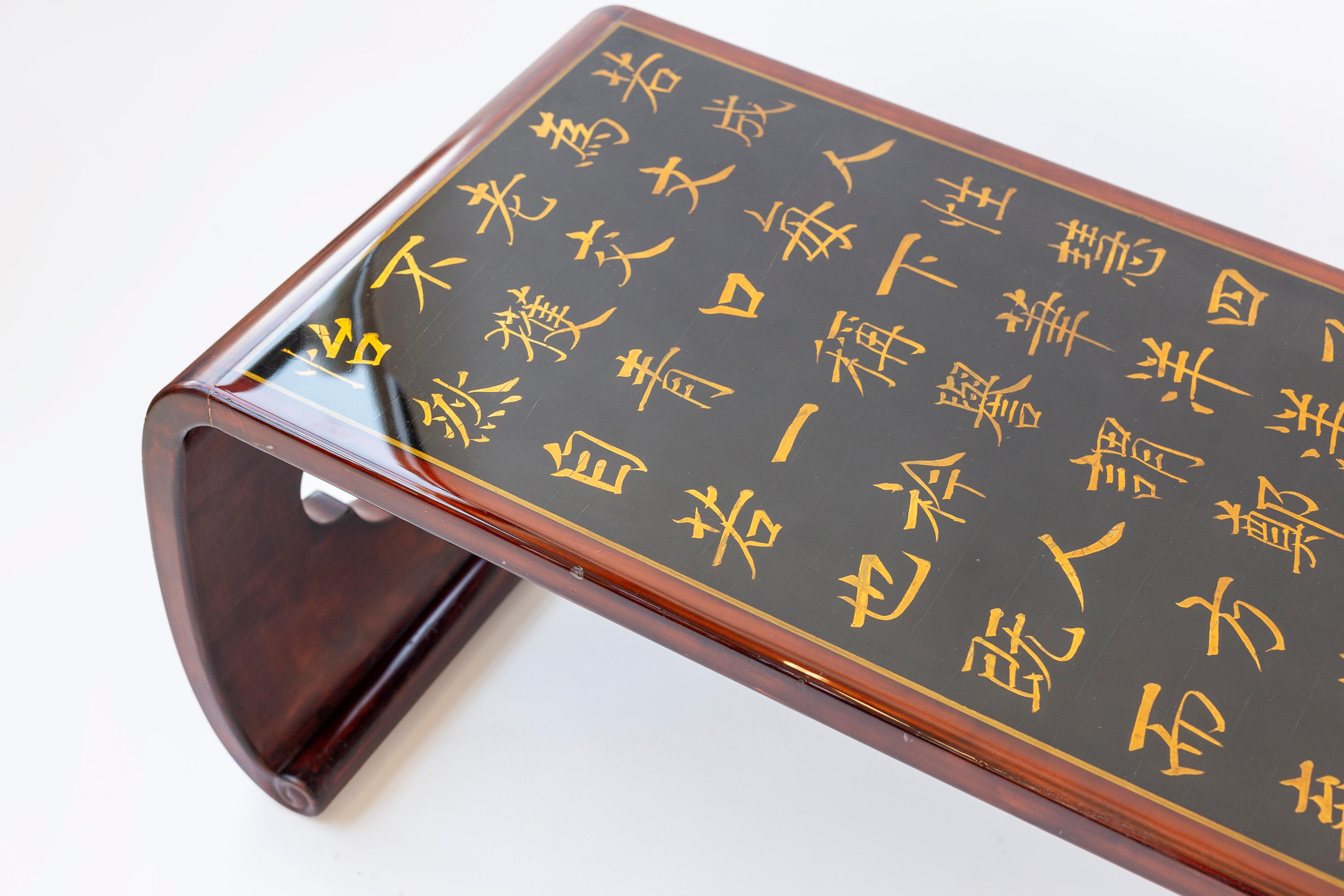 A vintage (c.1990's) Asian inspired waterfall coffee table, made by Gracie in New York.

The table has open areas on the legs at each end in a quatrefoil shape. 

An antique Chinese export calligraphy panel, originally part of a screen, has been
