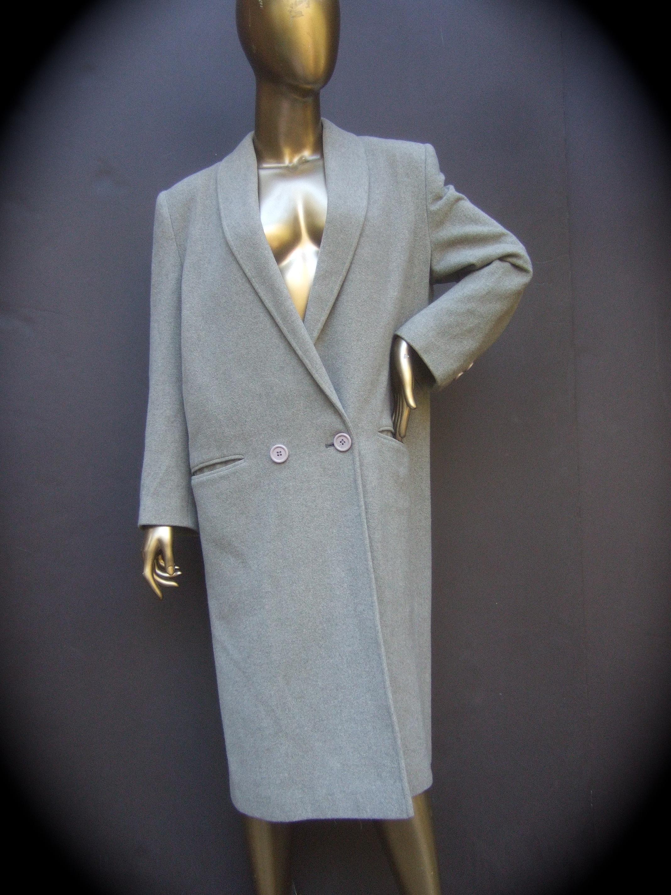 Cashmere classic heather gray women's overcoat c 1980s
The stylish winter coat is constructed with plush luxurious cashmere

Designed with a rounded elongated collar that secures with two horizontal resin buttons for an overlapped silhouette. A pair