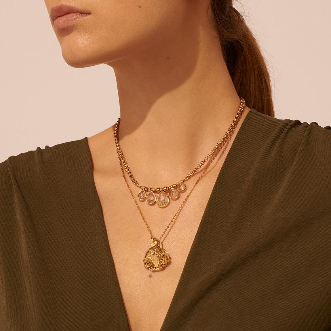 Collar de longitud media de la Colección Cachemire. Joyas talladas en forma de gota con cada piedra transformada en un estallido de luz. Acabado en oro amarillo.

Cristal de roca natural
Joyas sumergidas en un baño de oro de 24 quilates
80% latón