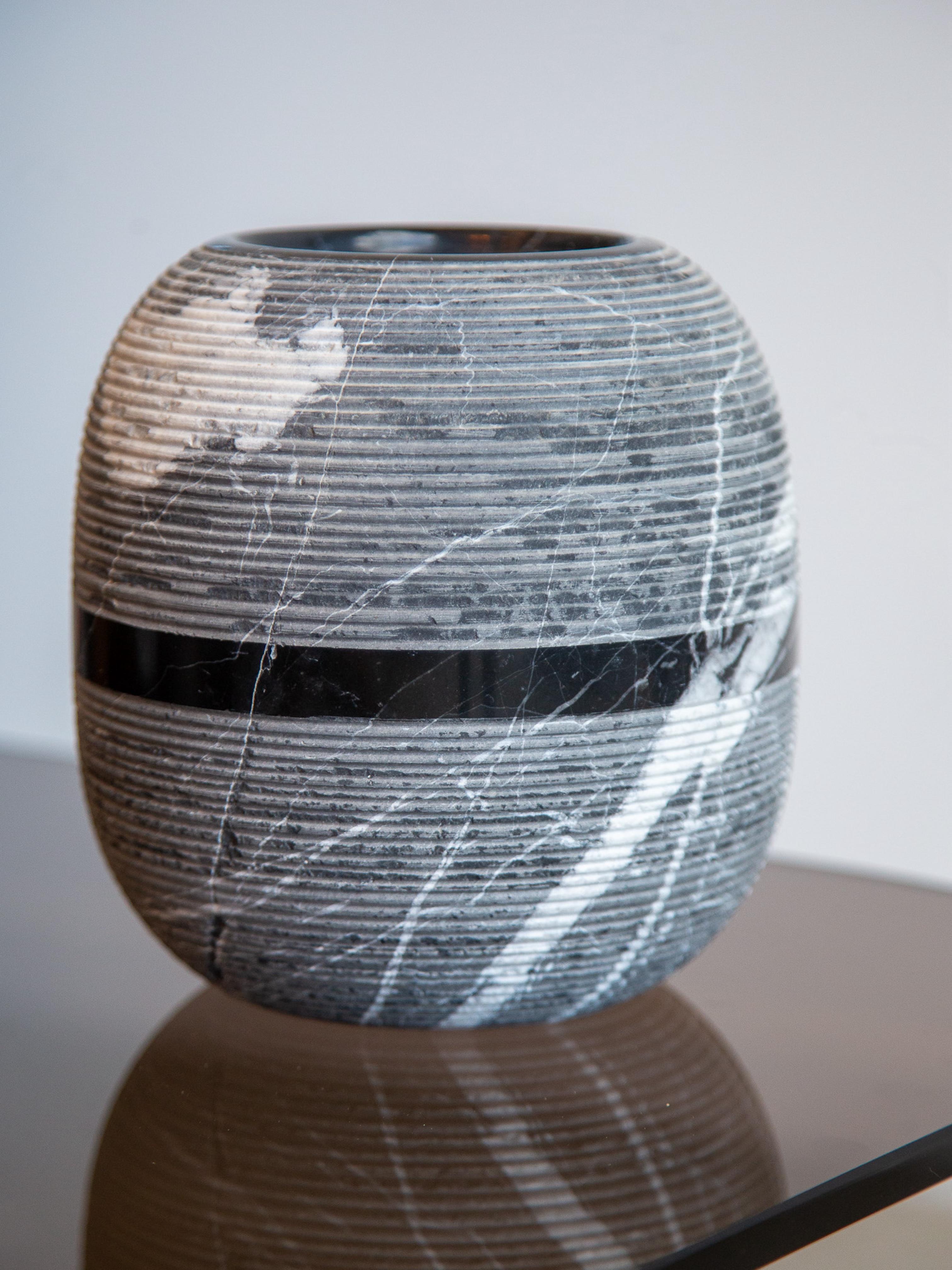 Il design incontra la gravità.
Realizzato in Italia da Casigliani, questo vaso scultura è una masterclass in forma, materiale e contrasto. Tornito a mano in marmo nero Marquina, presenta una superficie delicatamente scanalata, un bordo superiore
