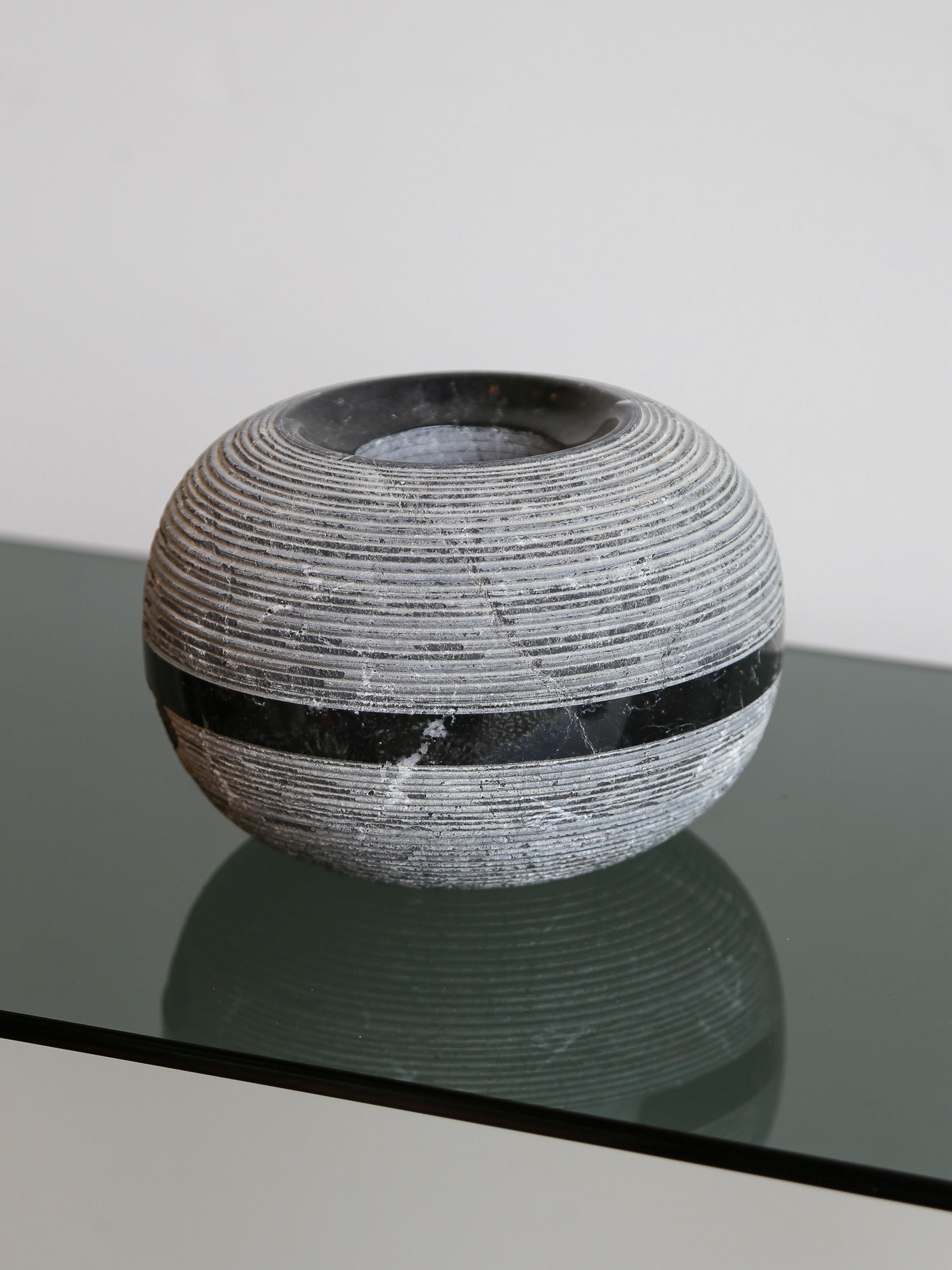 Il design incontra la gravità.
Realizzato in Italia da Casigliani, questo vaso scultura è una masterclass in forma, materiale e contrasto. Tornito a mano in marmo nero Marquina, presenta una superficie delicatamente scanalata, un bordo superiore