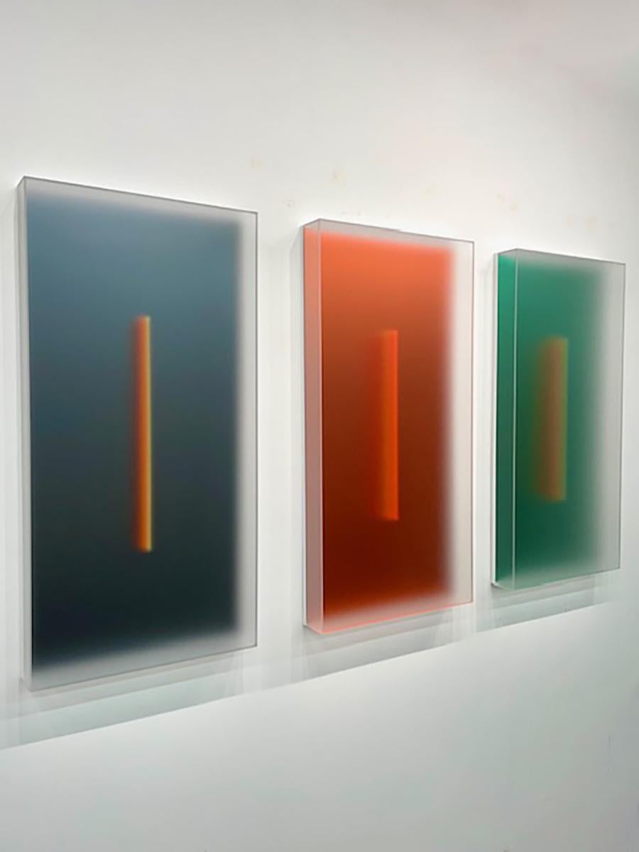In der ersten seiner neuesten Serie, Light-Glyphs, beleuchtet eine Reihe von Farben das Innere von durchscheinenden skulpturalen Kästen. Das Licht diffundiert durch ihre matten Oberflächen und macht die Farben im Inneren weich. In der Mitte fängt