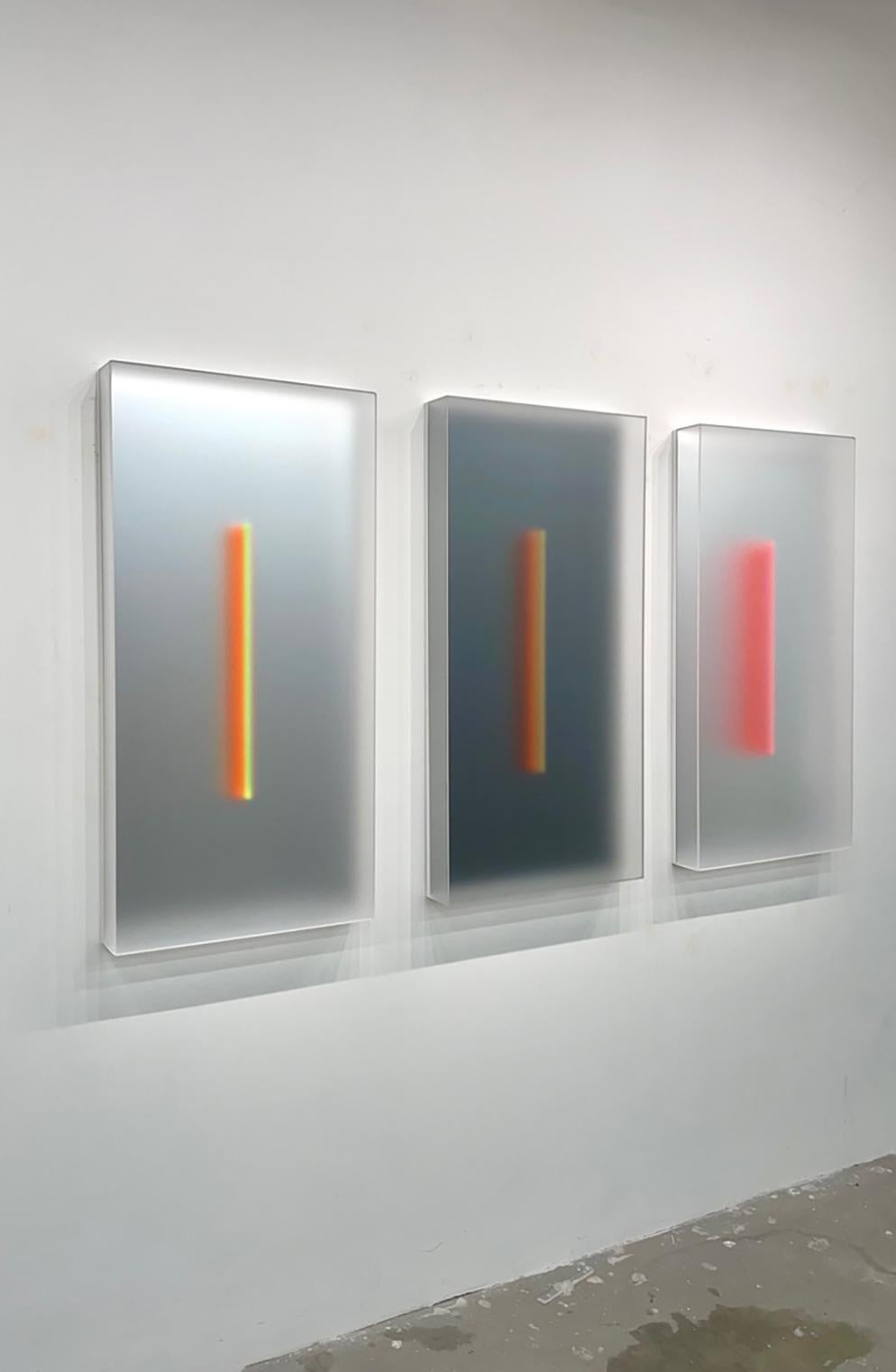In the first of his newest series, Light-Glyphs, a range of colors illuminate the interior of translucent sculptural boxes. Light diffuses through their frosted surfaces and softens the colors within. At the center, a thin blade of colorful