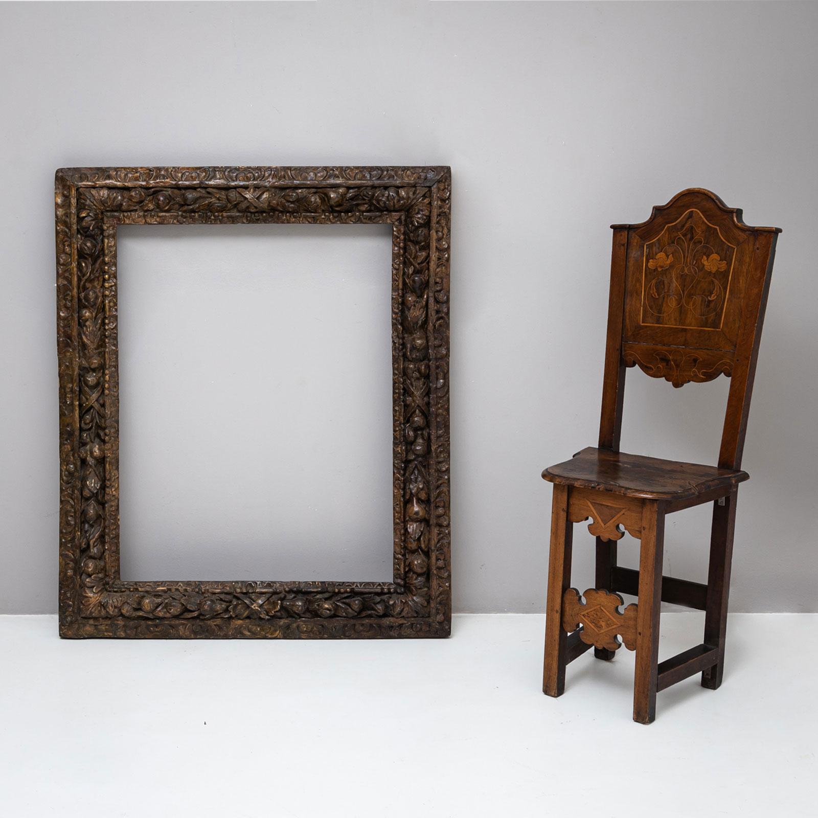 A tall rectangular frame featuring intricately carved and brown-patinated fruit and leaf motifs. The inner sight edge is adorned with a classic egg-and-dart frieze, while the outer frame is embellished with elaborate rocaille motifs.
The corners are