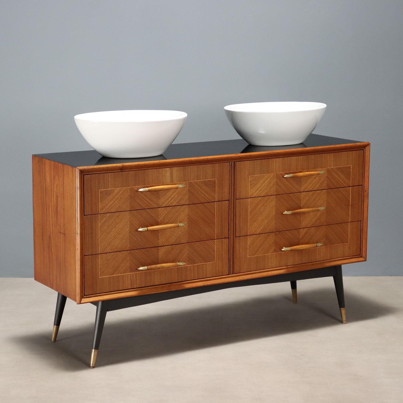 Cassettiera vintage di manifattura italiana riadattata a mobile bagno nei nostri laboratori di restauro ; presenta sei cassetti con maniglie in legno e ottone, gambe in legno di faggio tinto nero con puntali in ottone, piano in formica nera,