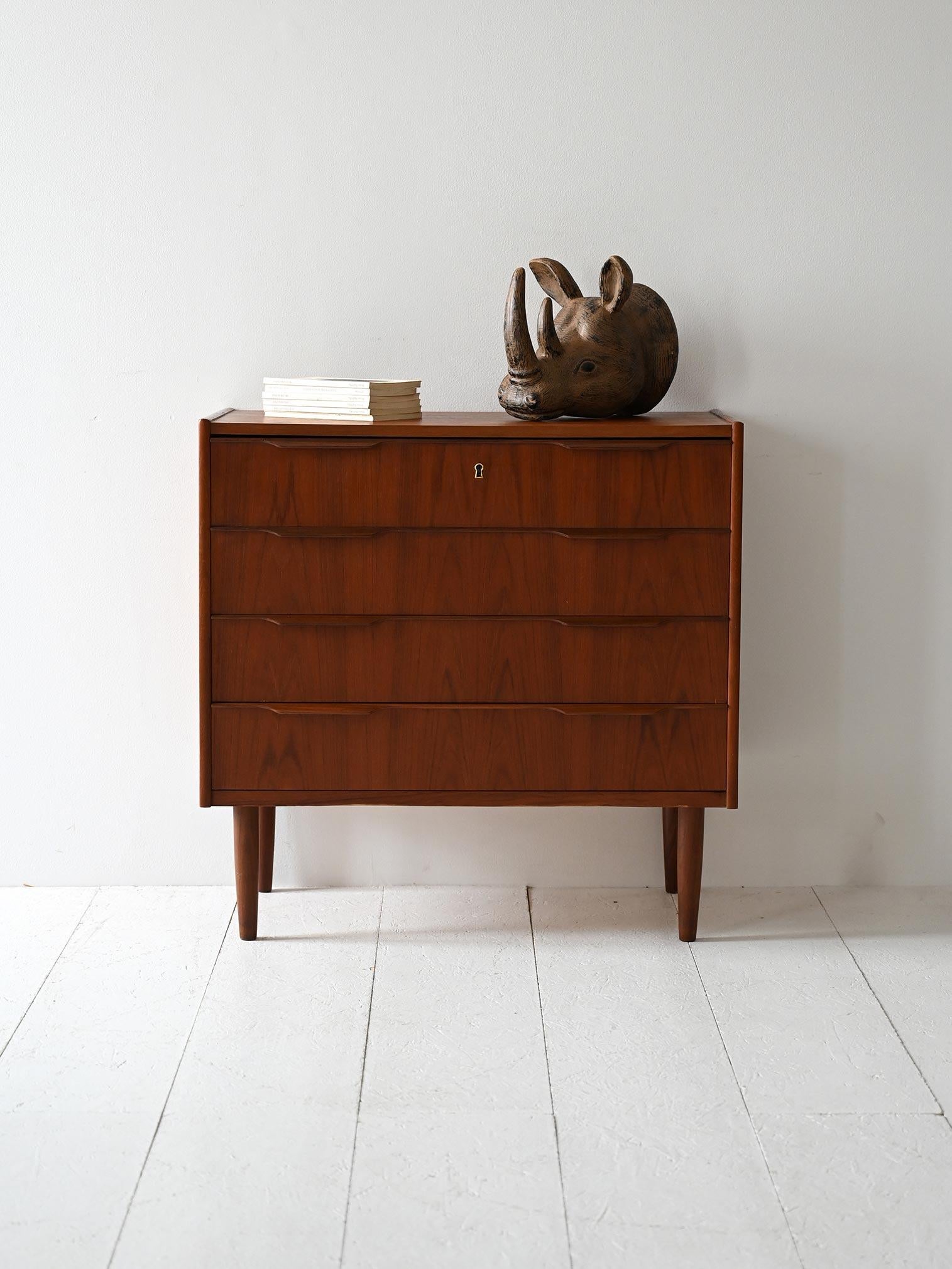 Cassettiera con quattro cassetti, maniglie sagomate a presa integrata e finitura in teak fiammato dal tono profondo.

Eleganza sobria e proporzioni ben definite per questa cassettiera danese degli anni ’60. I quattro cassetti sono scanditi da