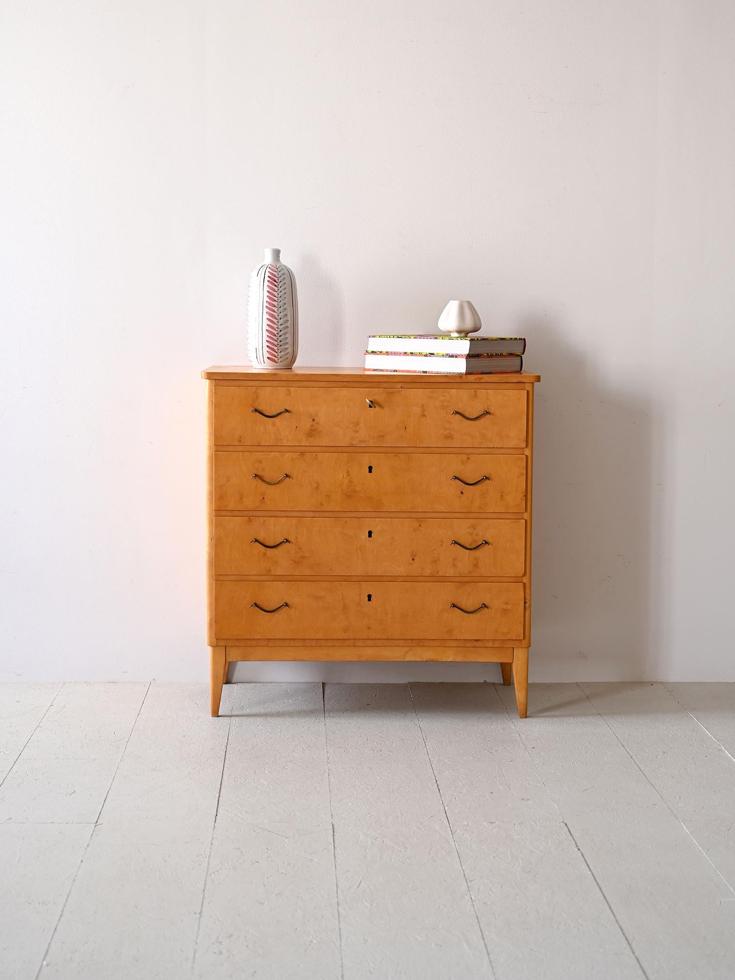 This 1950s Scandinavian chest of drawers, made of birch wood, has a functional look with its metal handles that stand out against a smooth surface. With a classic rectangular silhouette and angled legs, the cabinet offers an effective, no-frills