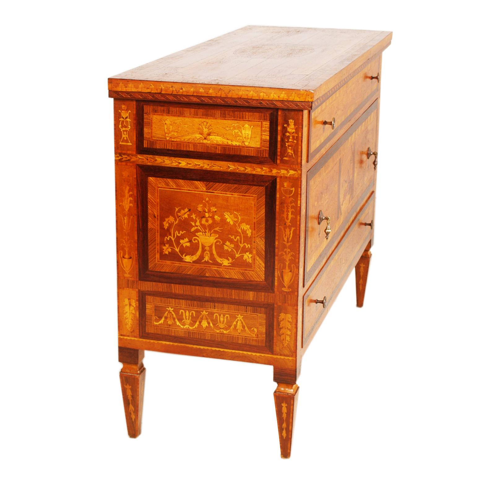 Comò Milanese di Meroni & Fossati, inizio del XX secolo. Mobile Maggiolini in stile Luigi XVI riccamente intarsiato in legni di noce,  palissandro, acero, faggio e legni da frutto con decori  di grande piacevolezza. Cassettone munito di tre cassetti