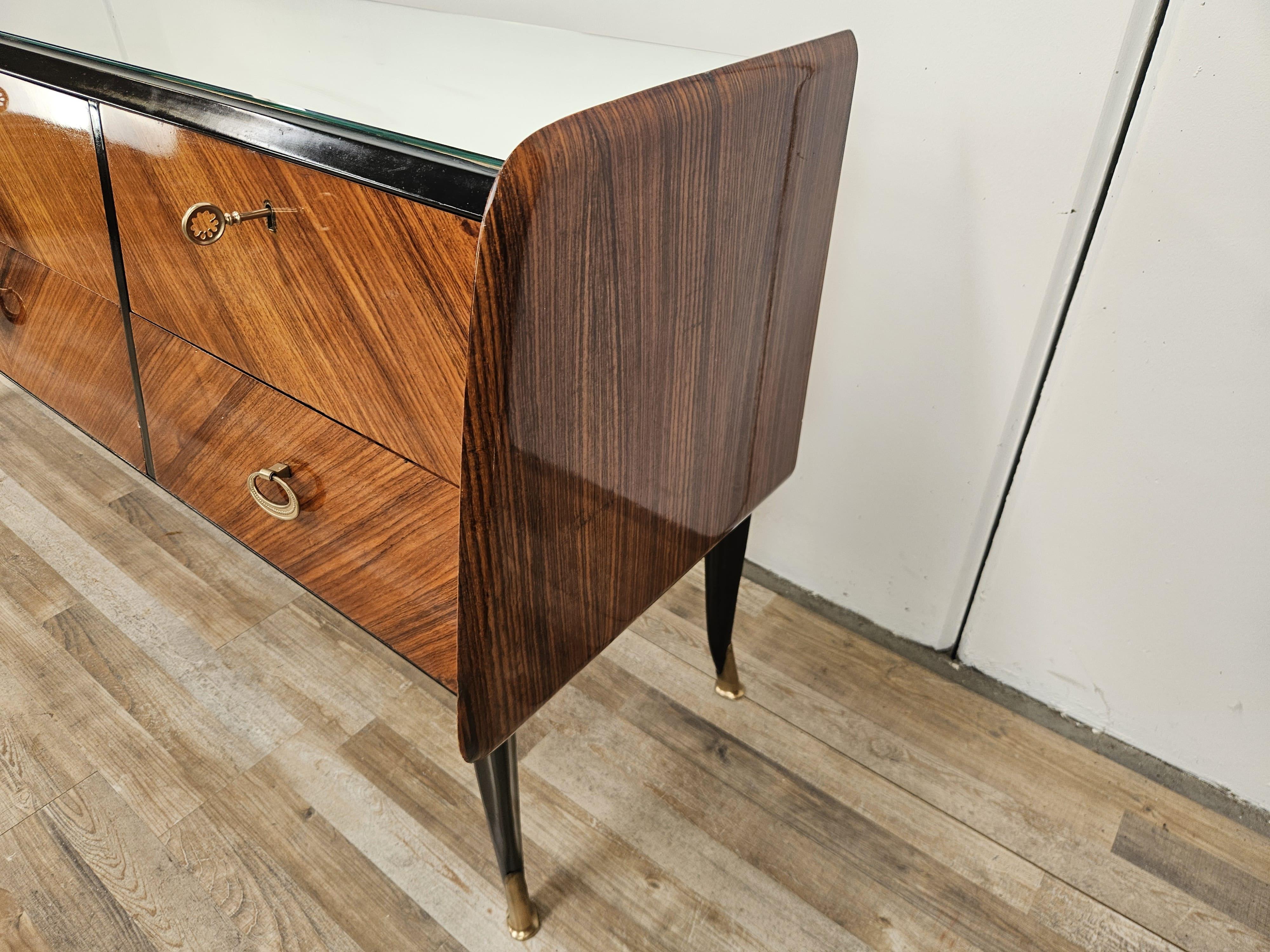 Commode vintage des années 1950 recouverte d'acajou avec six grands tiroirs robustes avec des poignées en laiton et des clés décoratives.

La commode a été huilée et présente des signes normaux d'usure dus à l'âge et à l'utilisation.