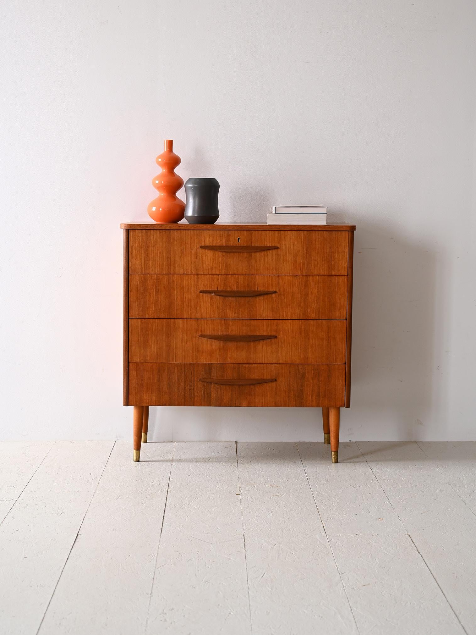 Scandinavian cabinet with 4 drawers and brass ferrule.

This teak-framed one embodies the functionality and elegant design typical of the mid-century period. The 'wooden handle of the drawers, a distinctive feature of the cabinet, enhances its