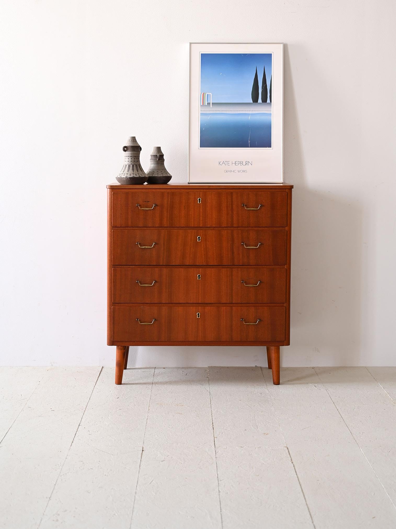 Scandinavian cabinet with 4 drawers with golden metal handle.

Scandinavian craftsmanship is expressed in this 1960s chest of drawers, with its refined design and functional metal handles. The bold tone of the wood is enhanced by the golden details