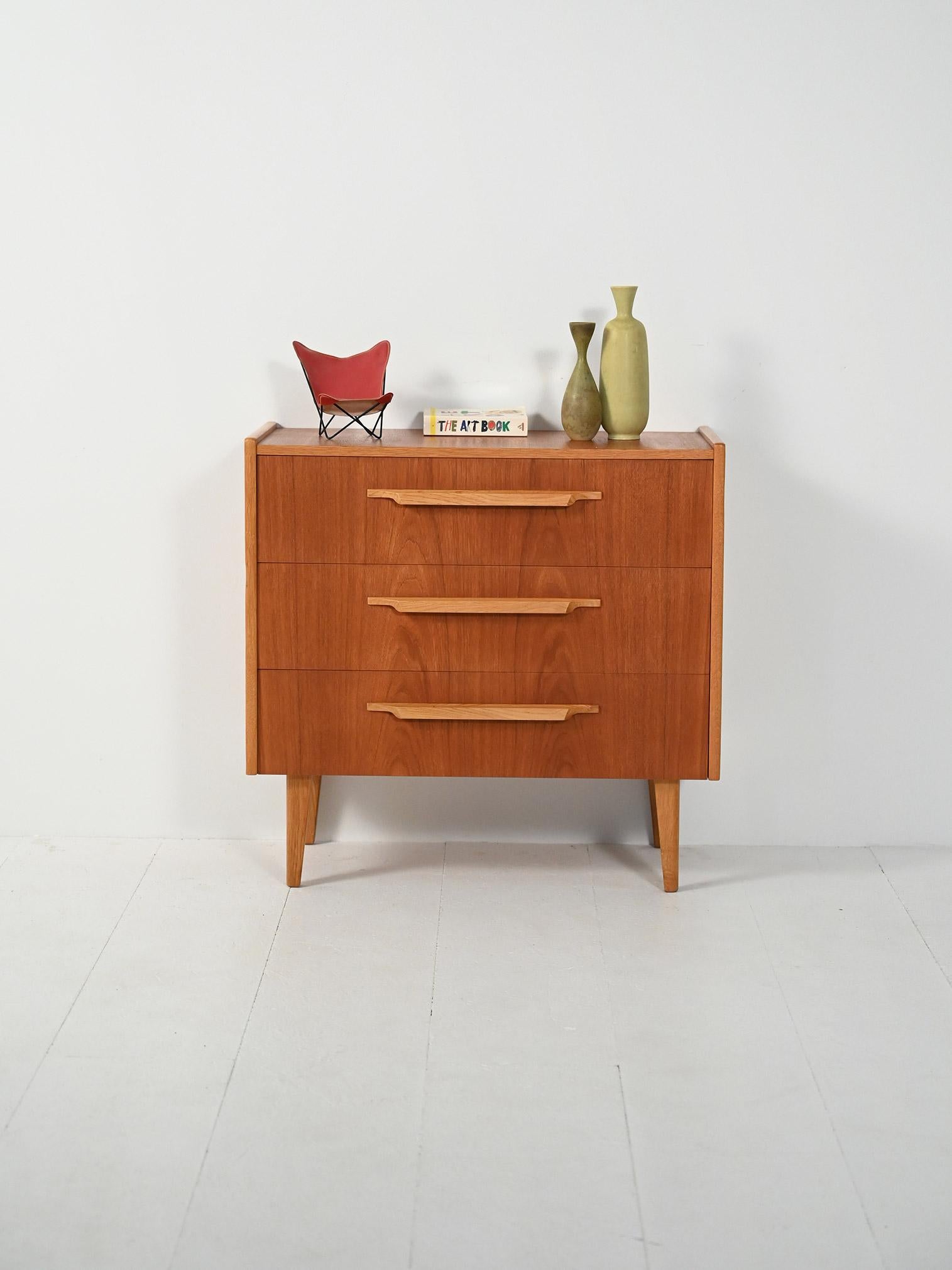 Cassettiera anni ’50-60 con frontali in teak, bordi e maniglie in rovere scolpito, gambe svasate.

Linea compatta e pulita che valorizza il contrasto tra teak caldo e rovere chiaro. Tre cassetti con maniglie a sbalzo finemente scolpite e struttura