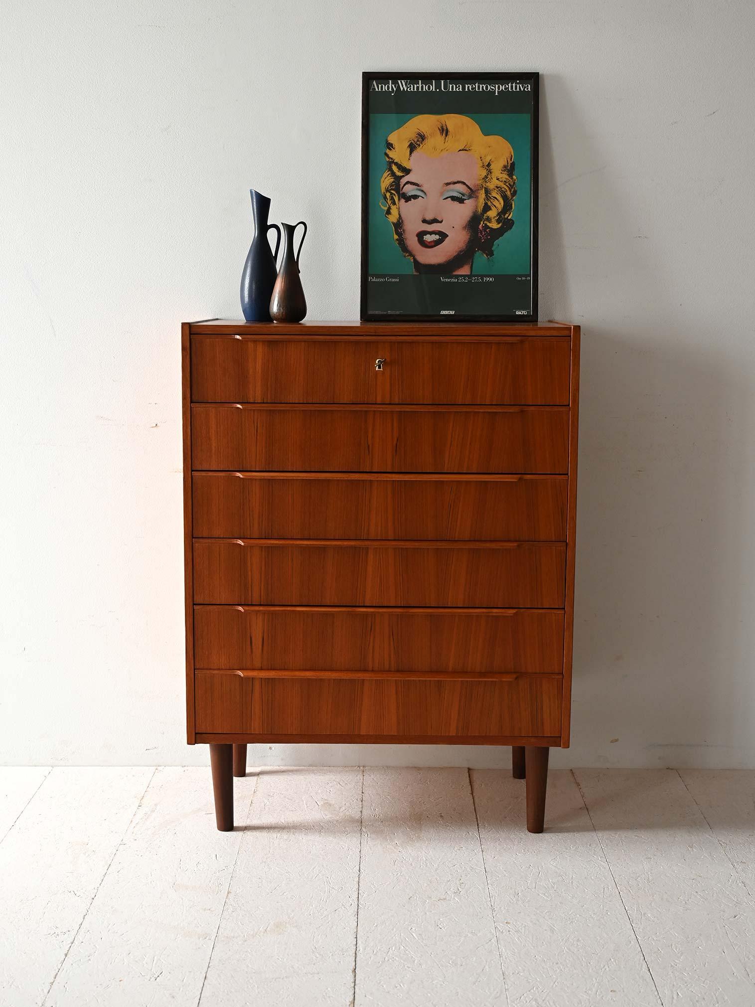 Cassettiera in teak con sei cassetti, maniglie intagliate e serratura con chiave originale sul primo cassetto.

Cassettiera scandinava vintage realizzata tra gli anni '50 e '60, in legno di teak con sei cassetti. Le maniglie intagliate a incavo