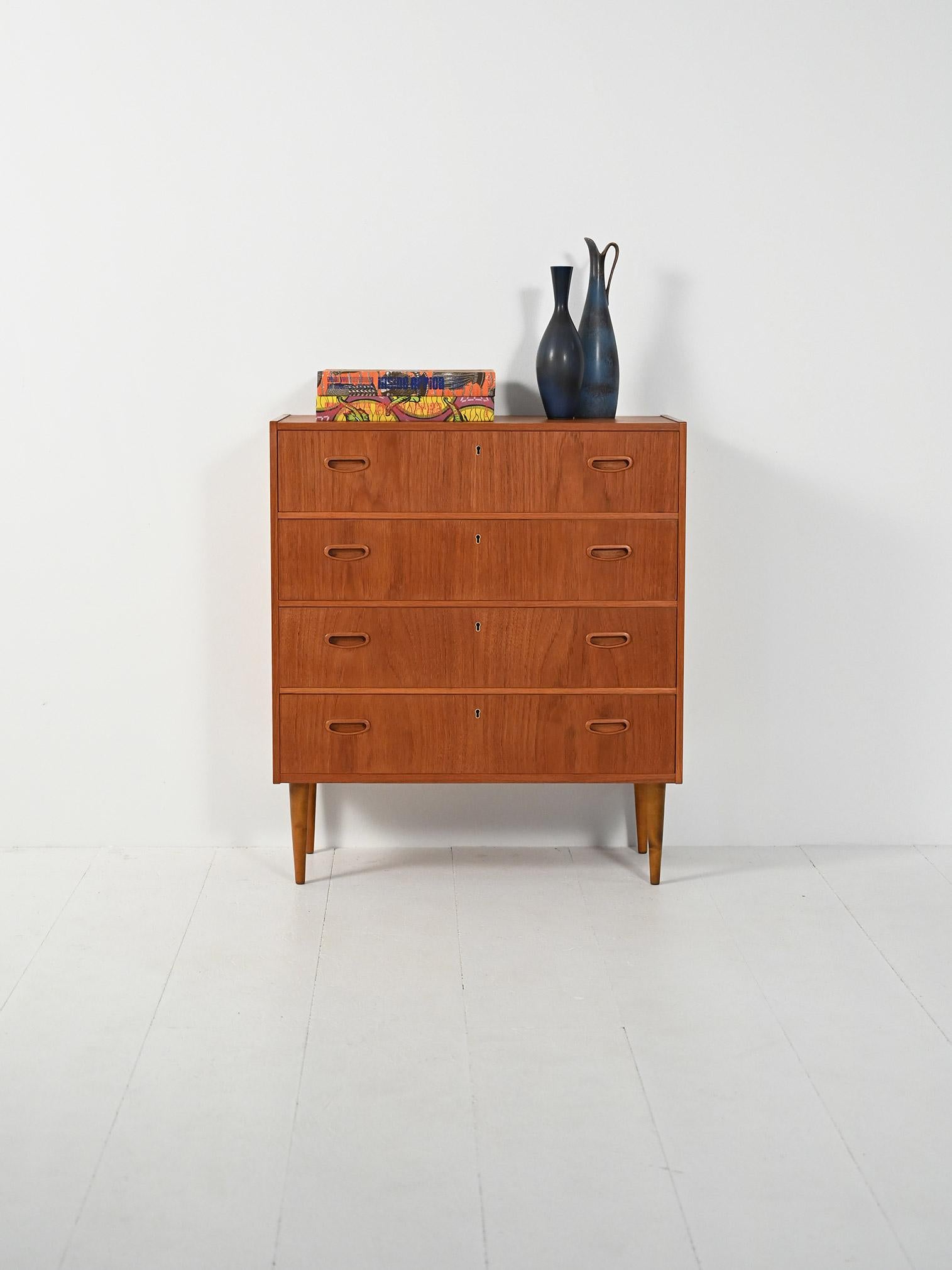 Cassettiera in teak con quattro cassetti e maniglie a incasso, struttura sobria su gambe tornite affusolate.

Elegante cassettiera scandinava in teak, anni ’50-60, con quattro cassetti dotati di maniglie a incasso. Linee ortogonali e proporzioni