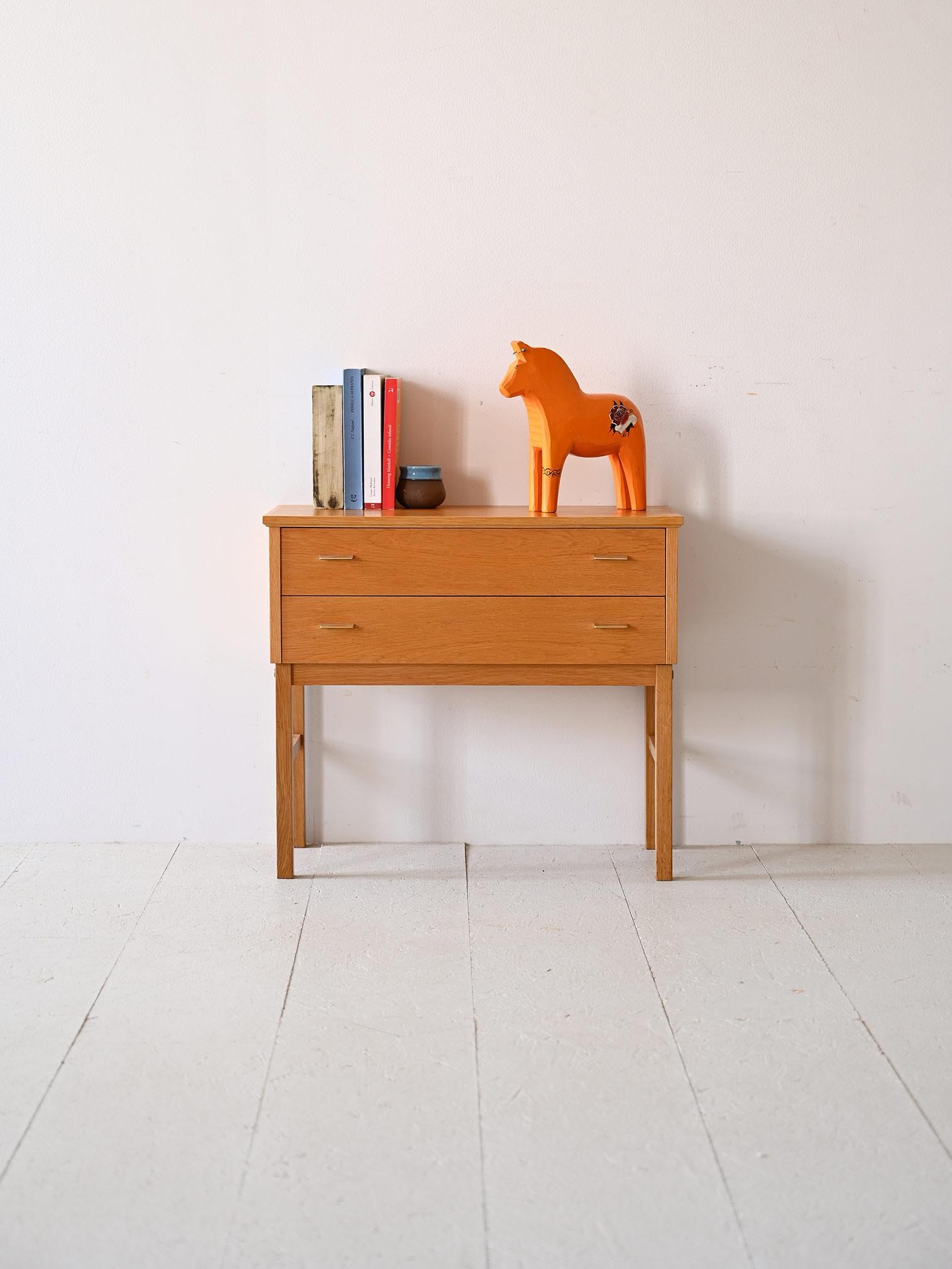 Comodino/ cassettiera con cassetti di manifattura scandinava prodotto nel 1969.
Questo particolare pezzo di design si distingue per la forma originale e per il caldo colore in rovere.

I due cassetti presentano un’impugnatura in metallo e le lunghe