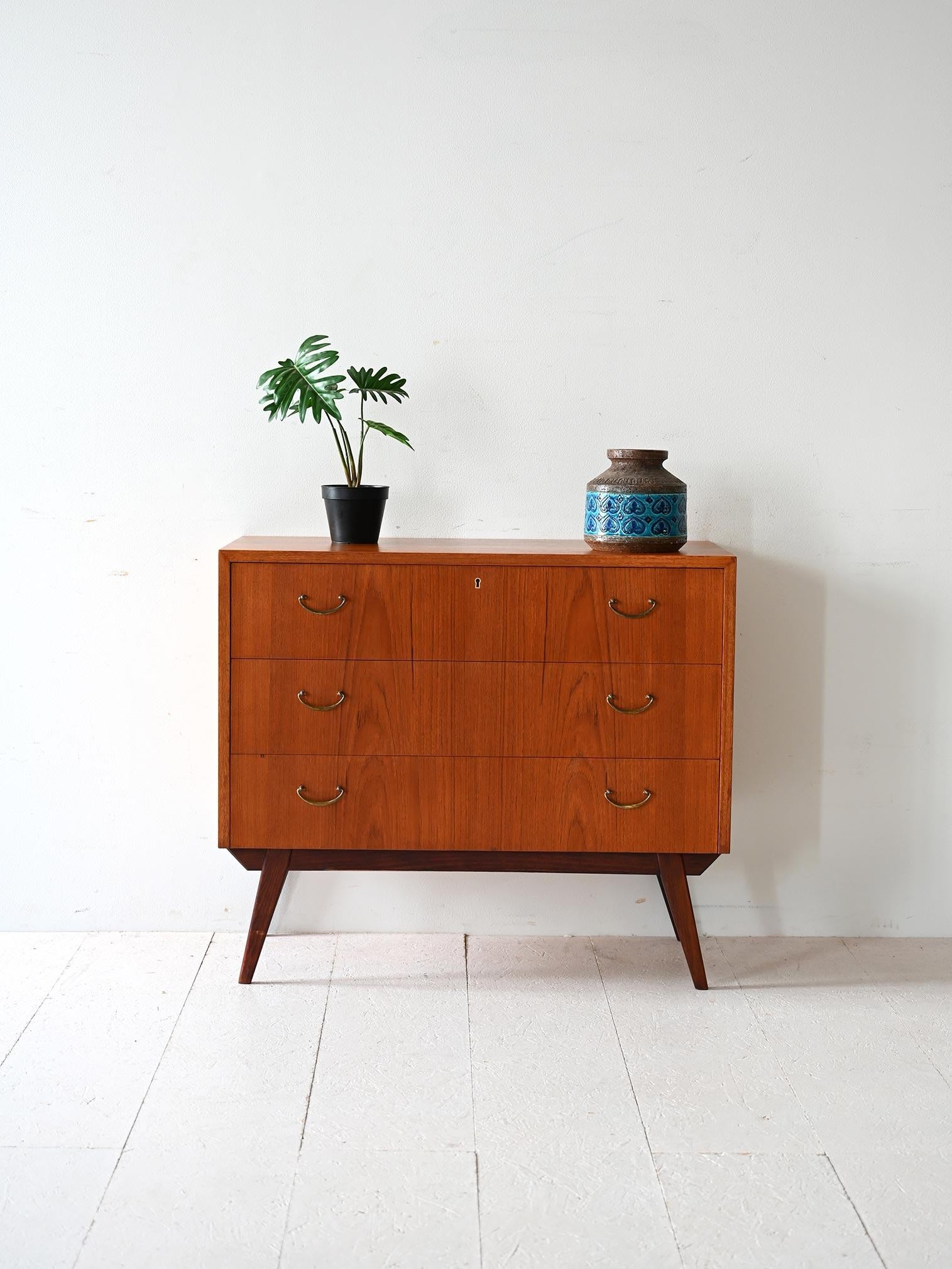 Vintage 1950s/60s chest of drawers with three drawers, teak frame and dark mahogany base, brass handles.

Scandinavian chest of drawers dating from the 1950s/60s. The frame is teak with dark mahogany base and legs. It features three drawers with